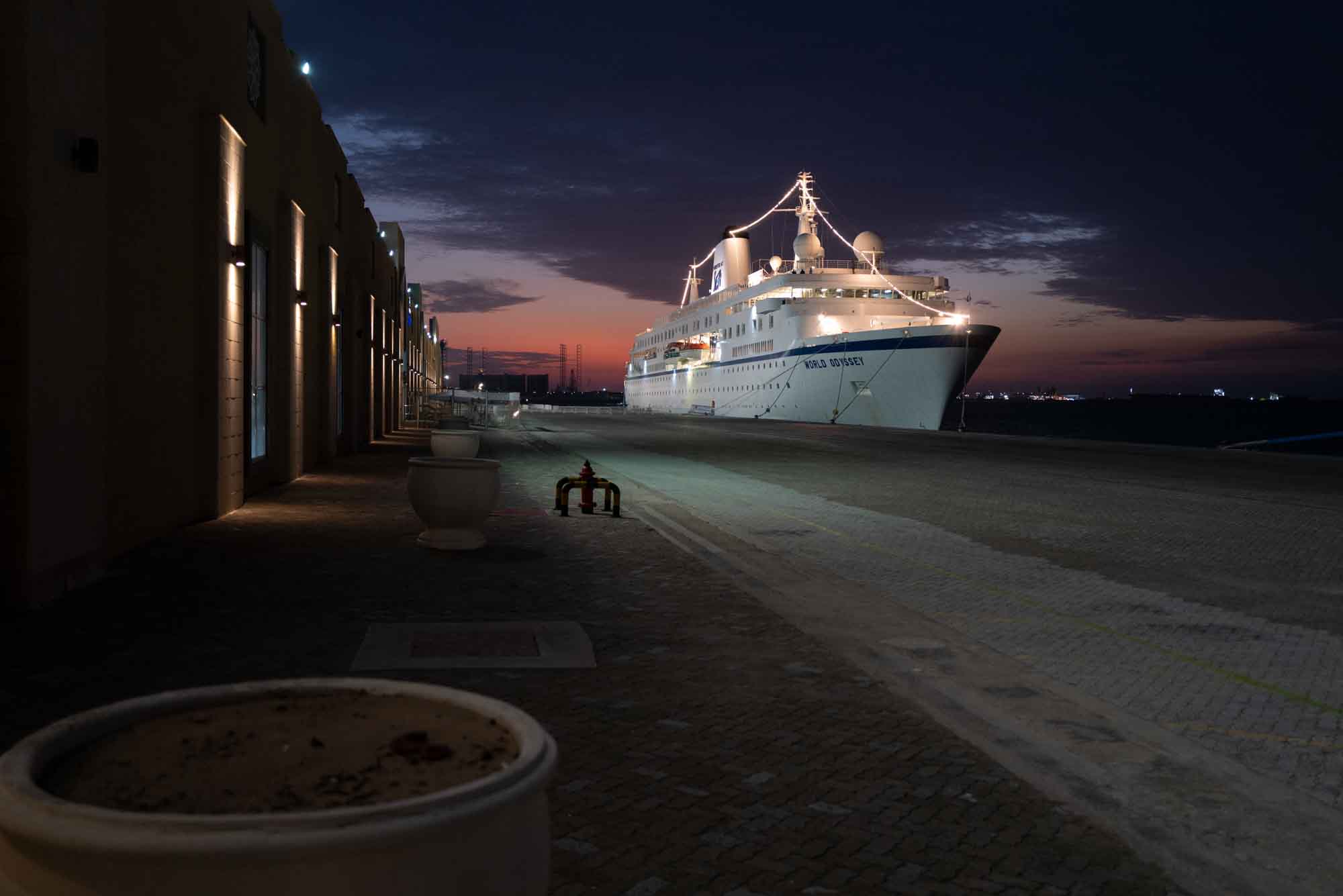 Cruise ship docked at a harbor during twilight, illuminated by soft lighting.