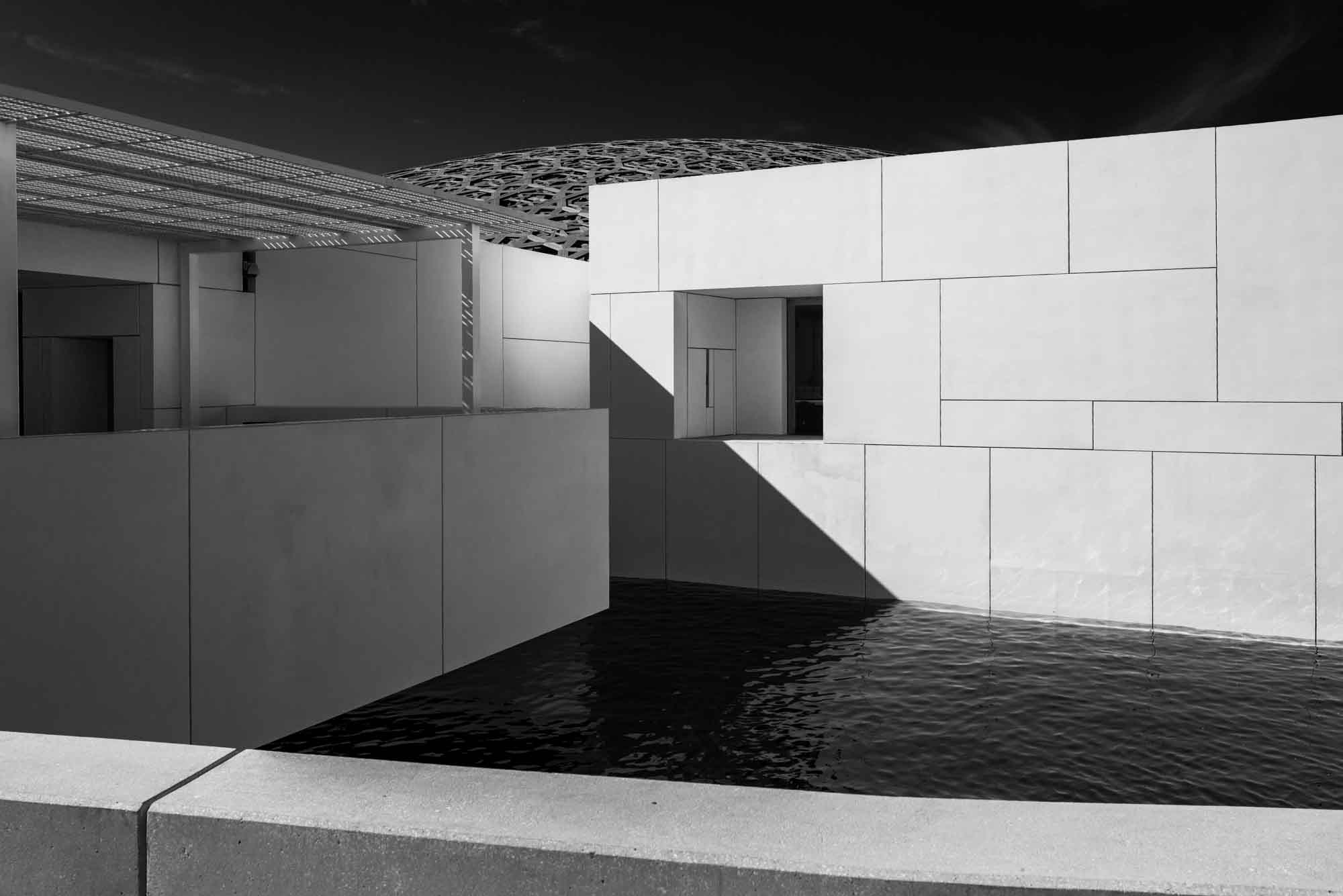 Modern architectural design with geometric structures and shadow play reflected on water. Black and white photography.