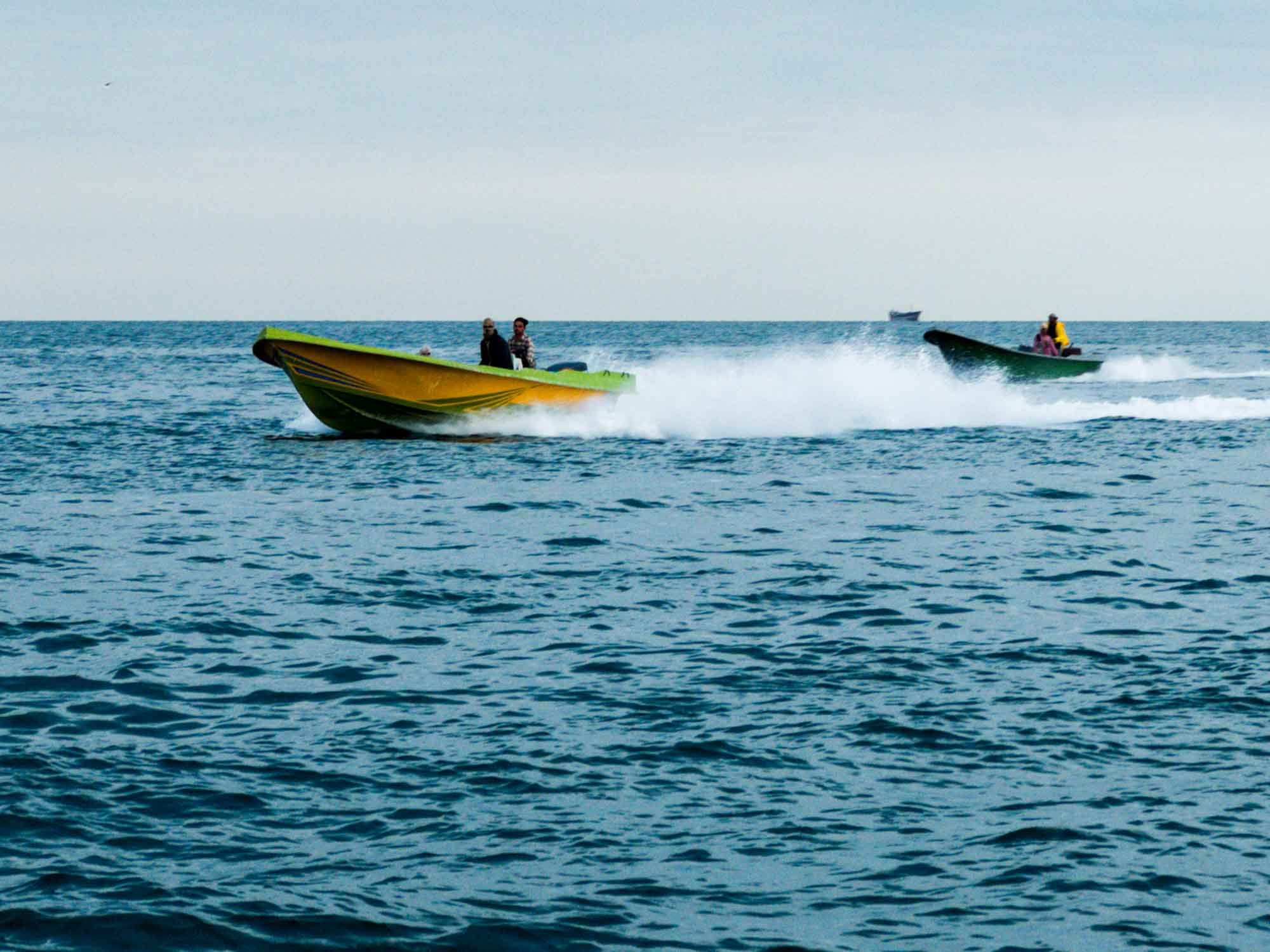 Speedboats racing across the ocean waves, creating a dynamic wake behind them.