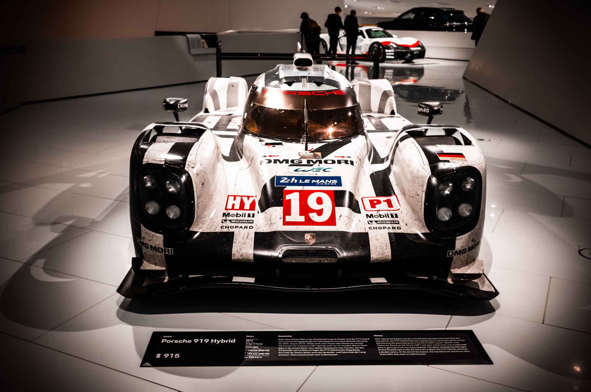 Race car exhibit featuring a Porsche 919 Hybrid with racing decals at an auto museum display.
