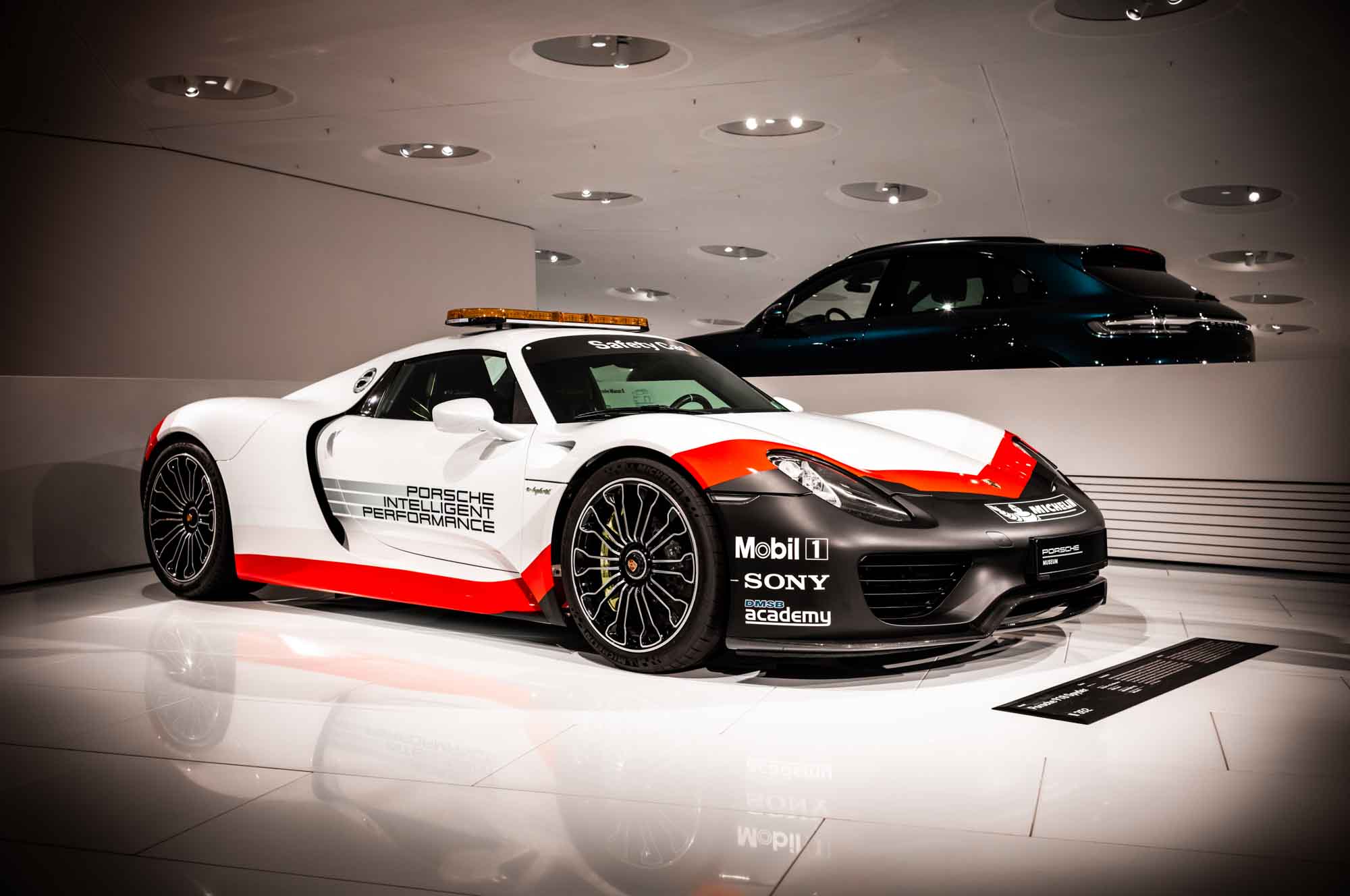 White and red Porsche sports car displayed in a modern showroom, showcasing sleek design and performance.