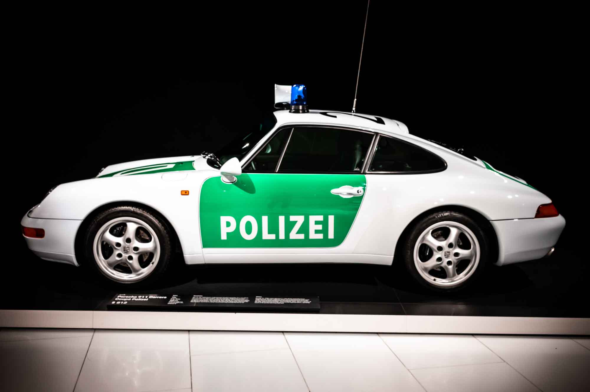 Vintage Porsche police car with green and white design, marked Polizei, displayed in a dark background setting.