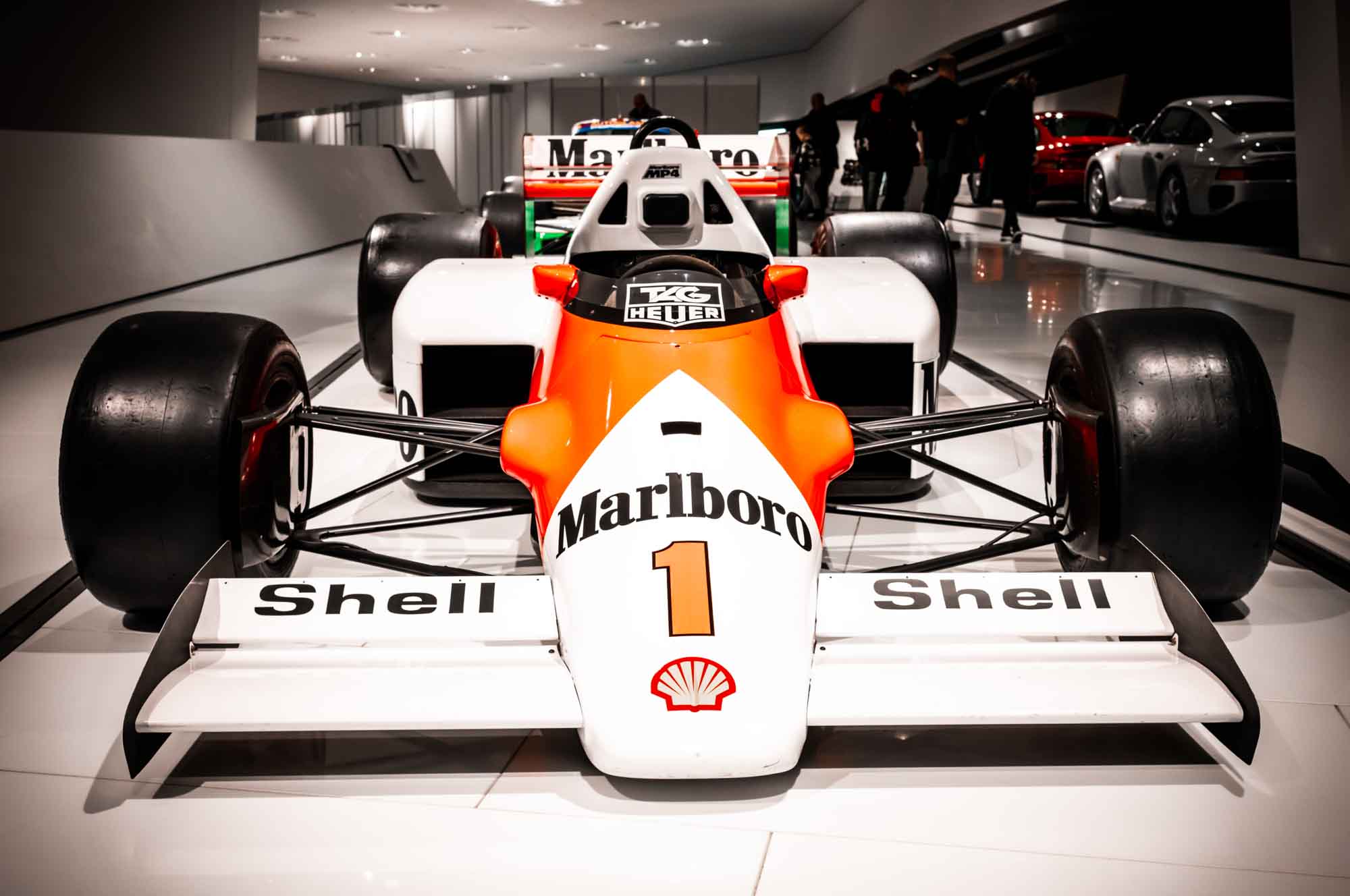 Front view of a classic Formula 1 race car with prominent branding on display in a modern gallery setting.