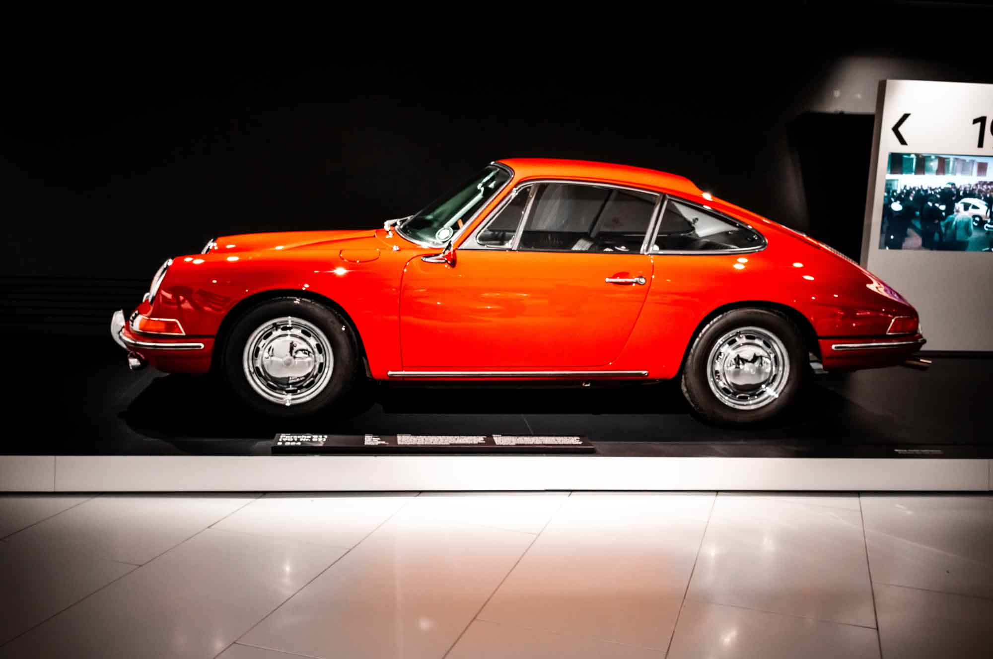 Classic red sports car on display, side view in a museum setting.