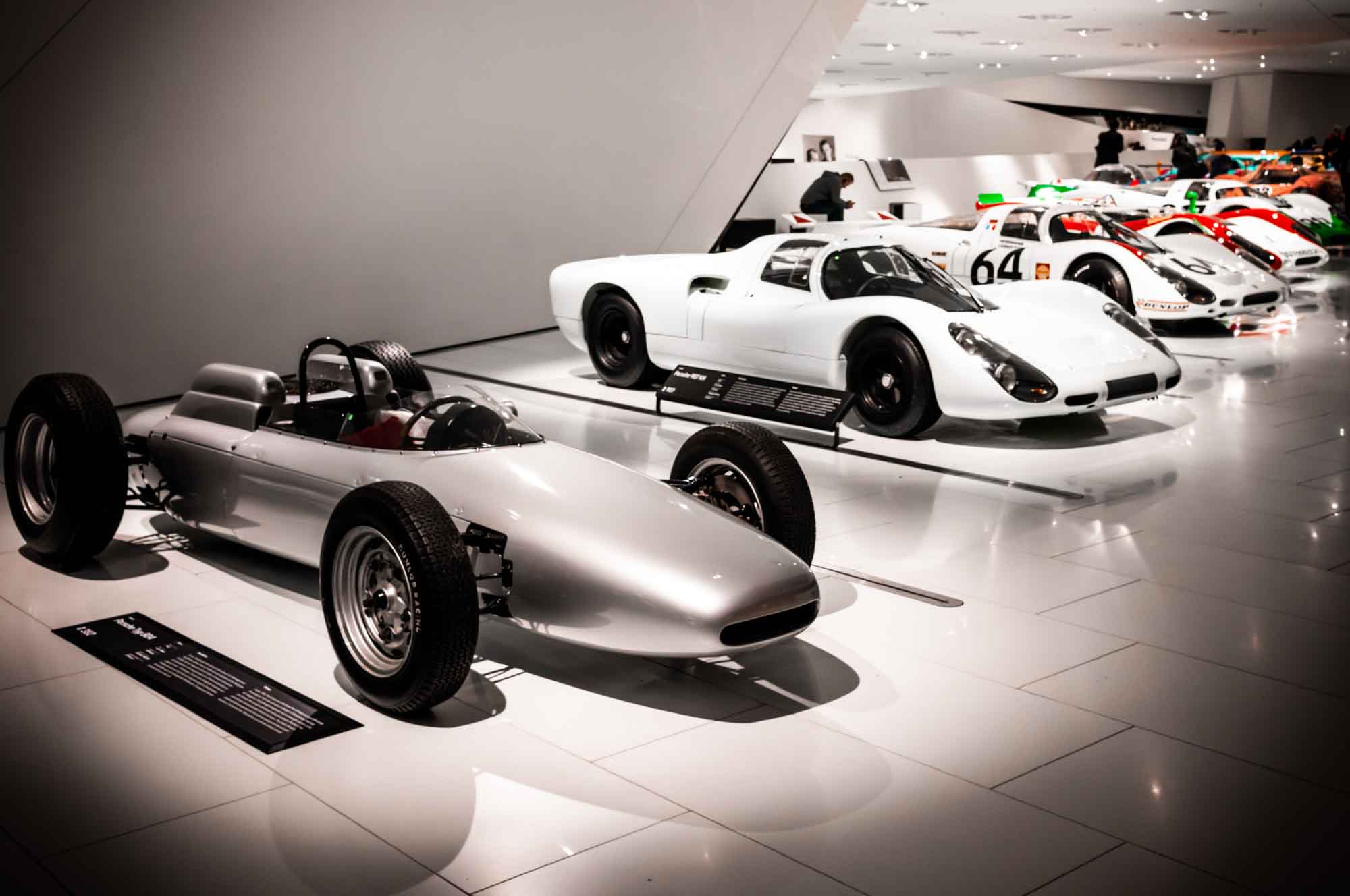 Vintage race cars displayed in a sleek, modern museum setting.