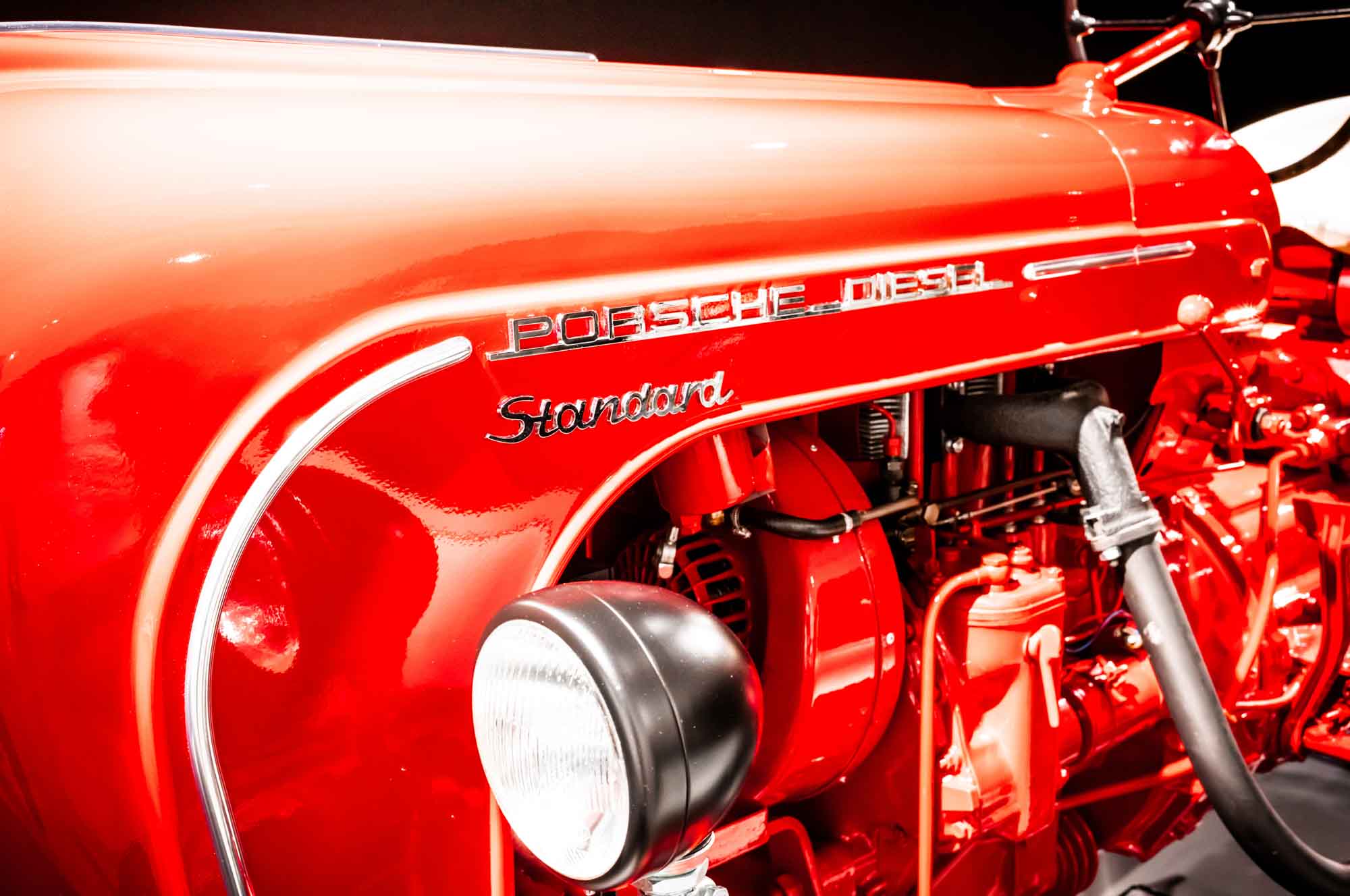 Close-up of a red vintage Porsche diesel tractor displaying the engine and front design details.
