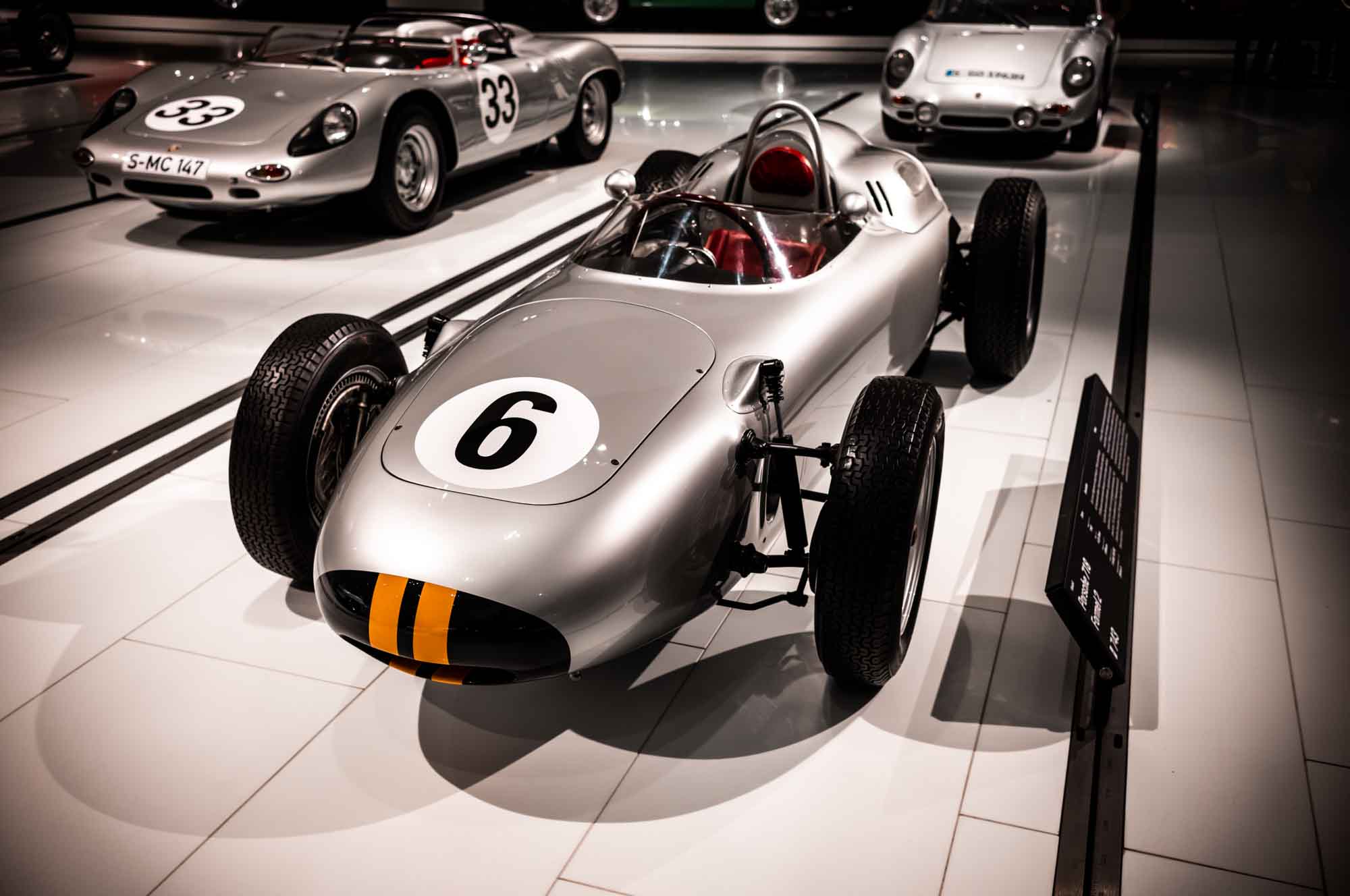 Vintage silver race car with number 6 on display in a museum setting.