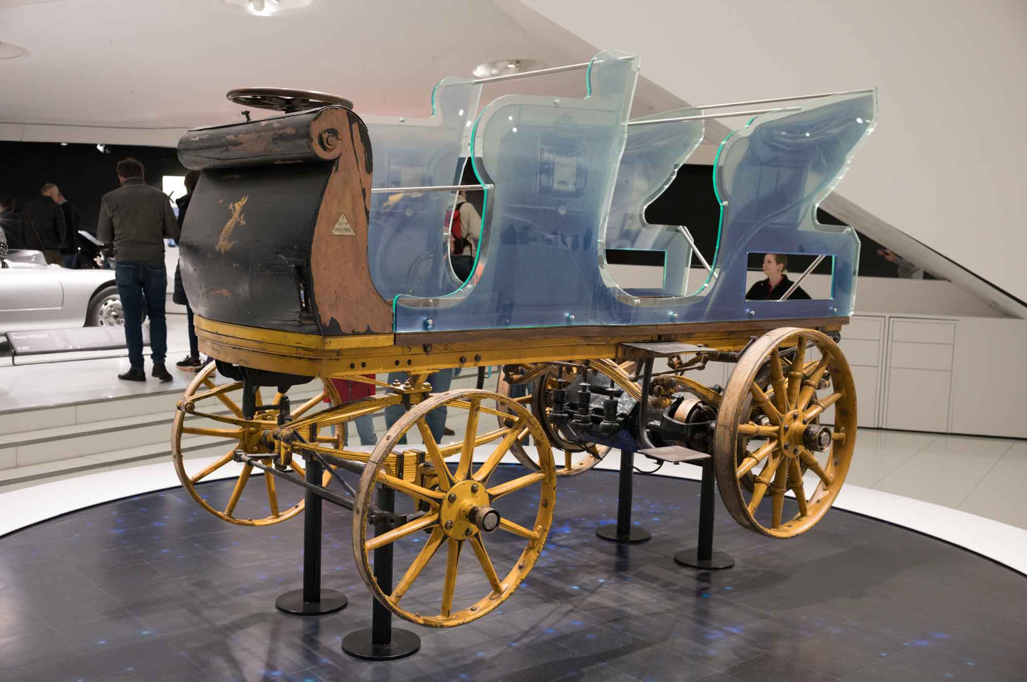 Antique horseless carriage on display in a museum, highlighting early automotive design and innovation.