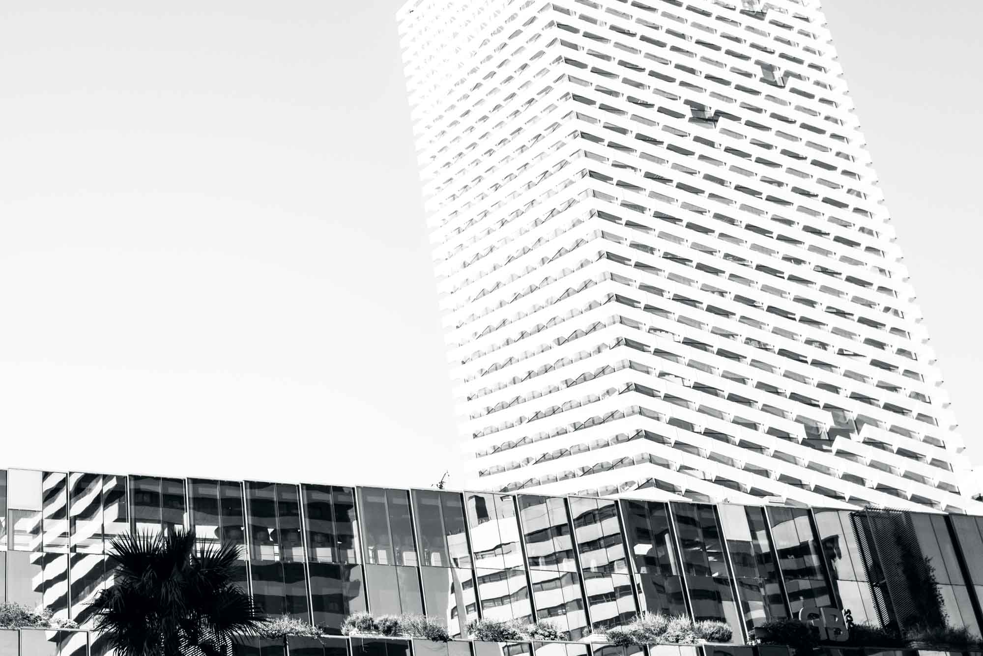 Black and white view of modern high-rise building with unique architectural design against the sky.