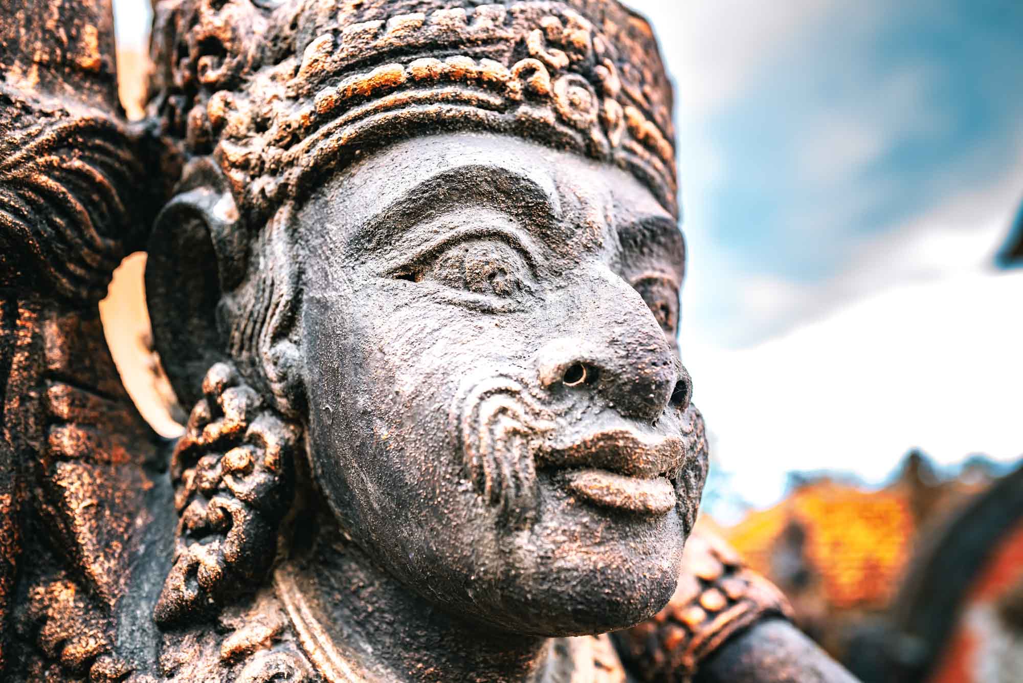Close-up of a detailed stone sculpture with intricate carvings against a blue sky background.