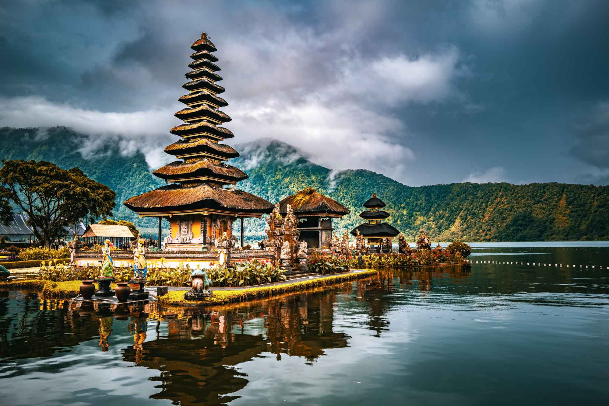 Scenic view of Ulun Danu Beratan Temple on Lake Bratan in Bali, Indonesia, with mountains and clouds in the background.