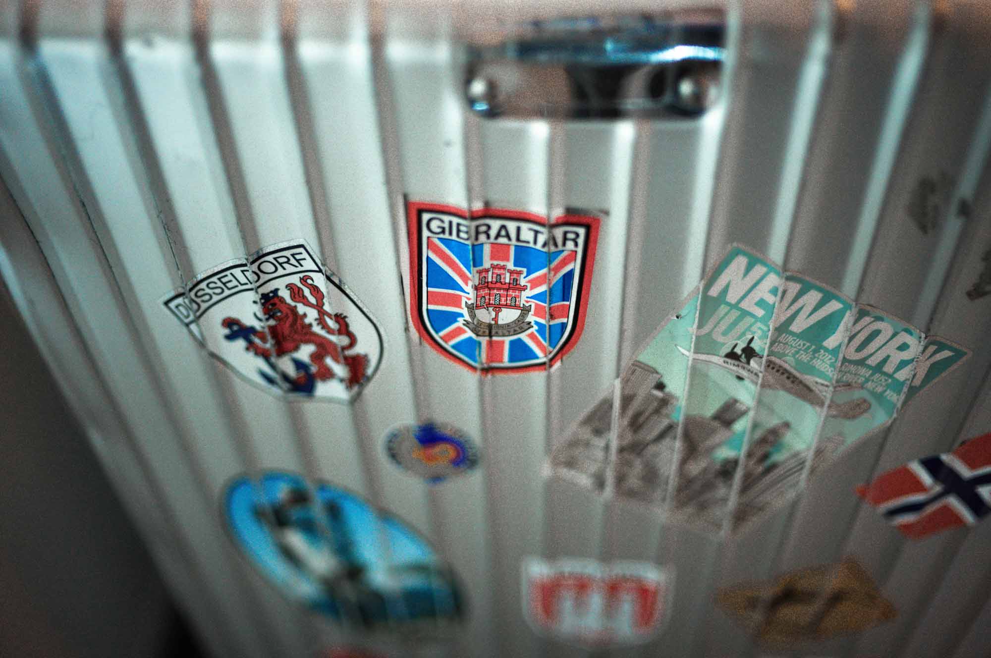 Travel stickers on a suitcase showing destinations like Düsseldorf, Gibraltar, and New York.