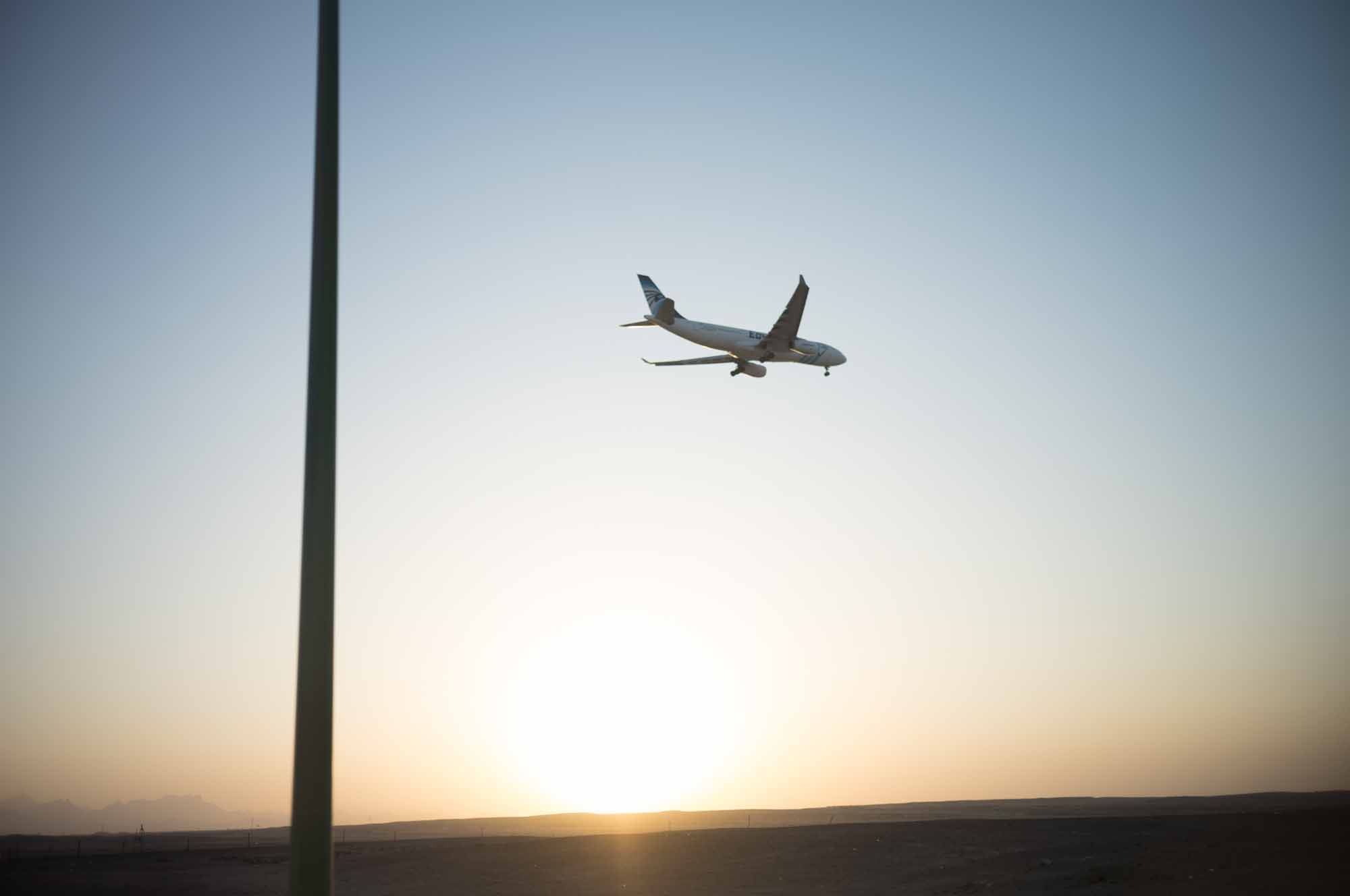 Airplane flying at sunrise with clear sky, symbolizing travel and new beginnings.