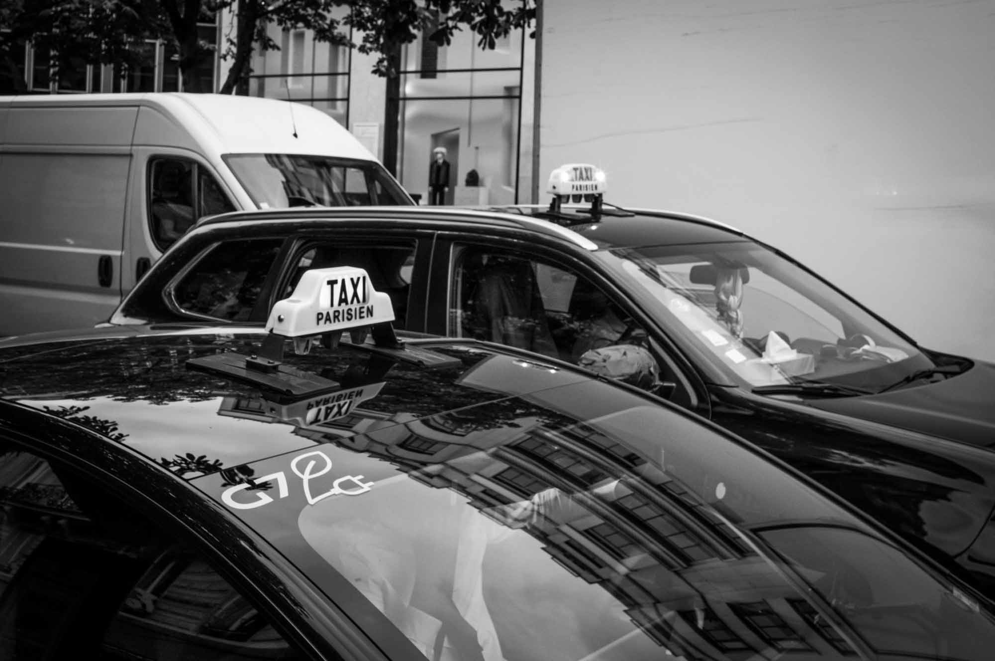 Paris taxis parked on a city street in black and white.