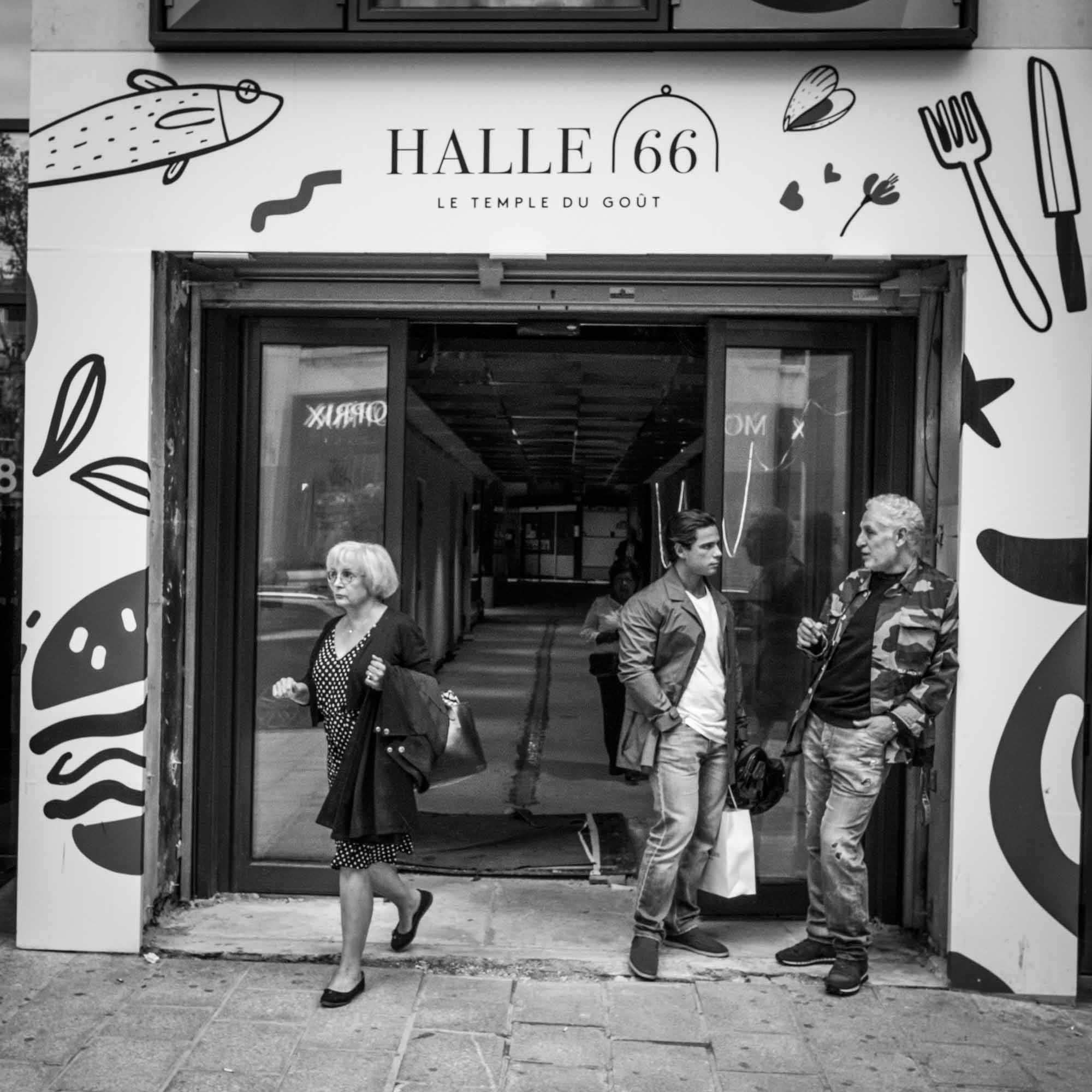 Visitors outside Halle 66 market in black and white, Paris street scene with murals.