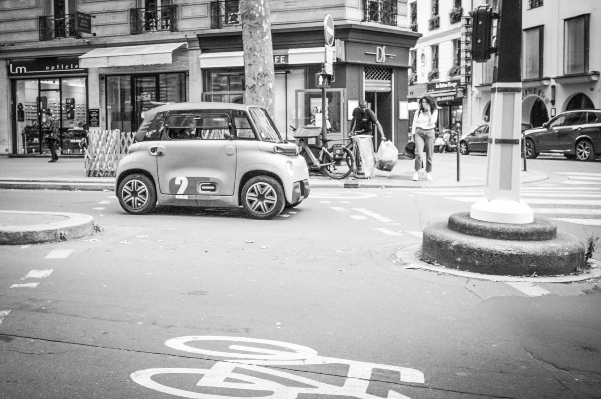 Compact car on a city street with bike lane in urban setting, monochrome photo.