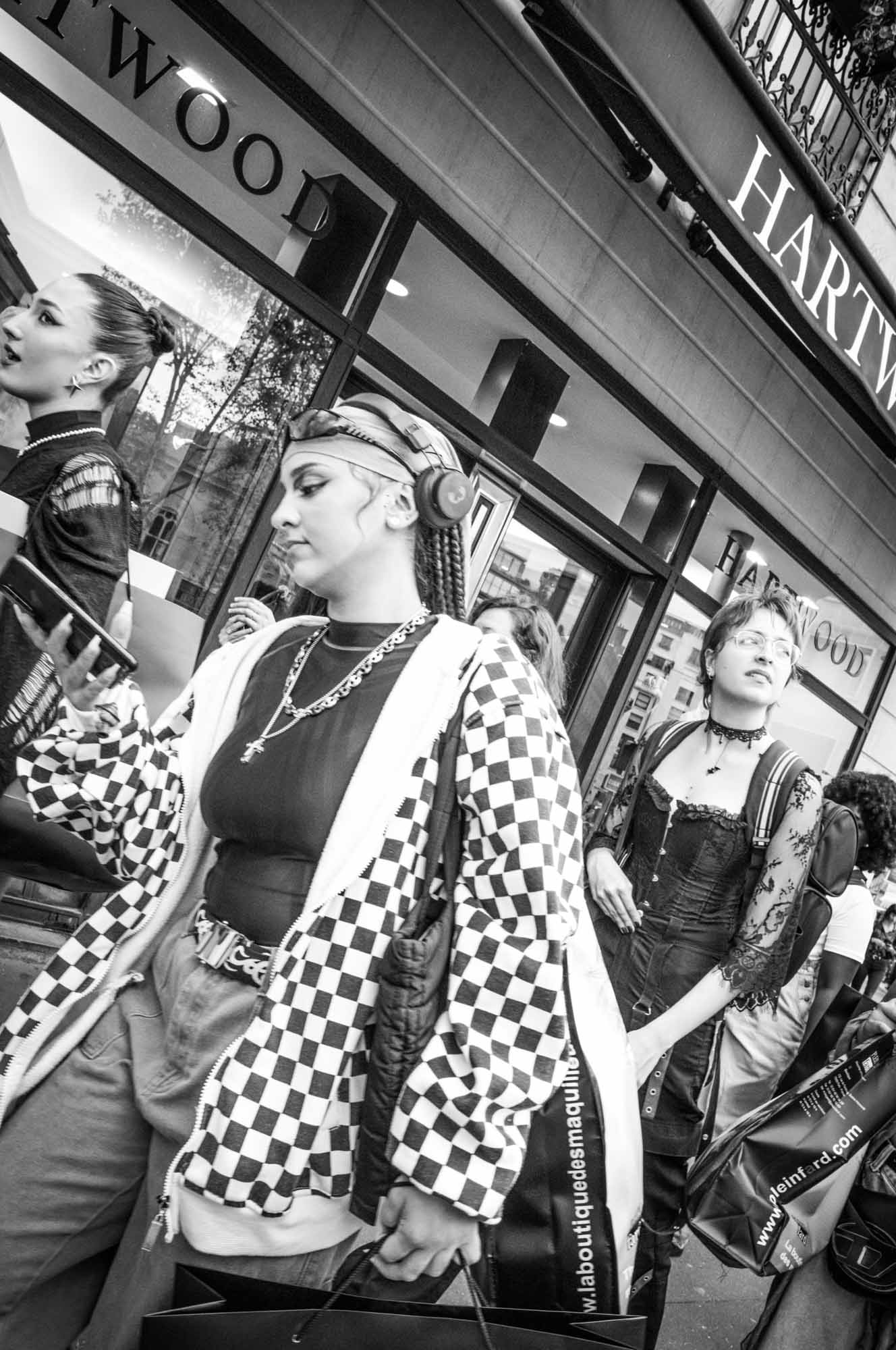 Street fashion: stylish people walking with shopping bags in front of Hartwood store. Black and white photo.