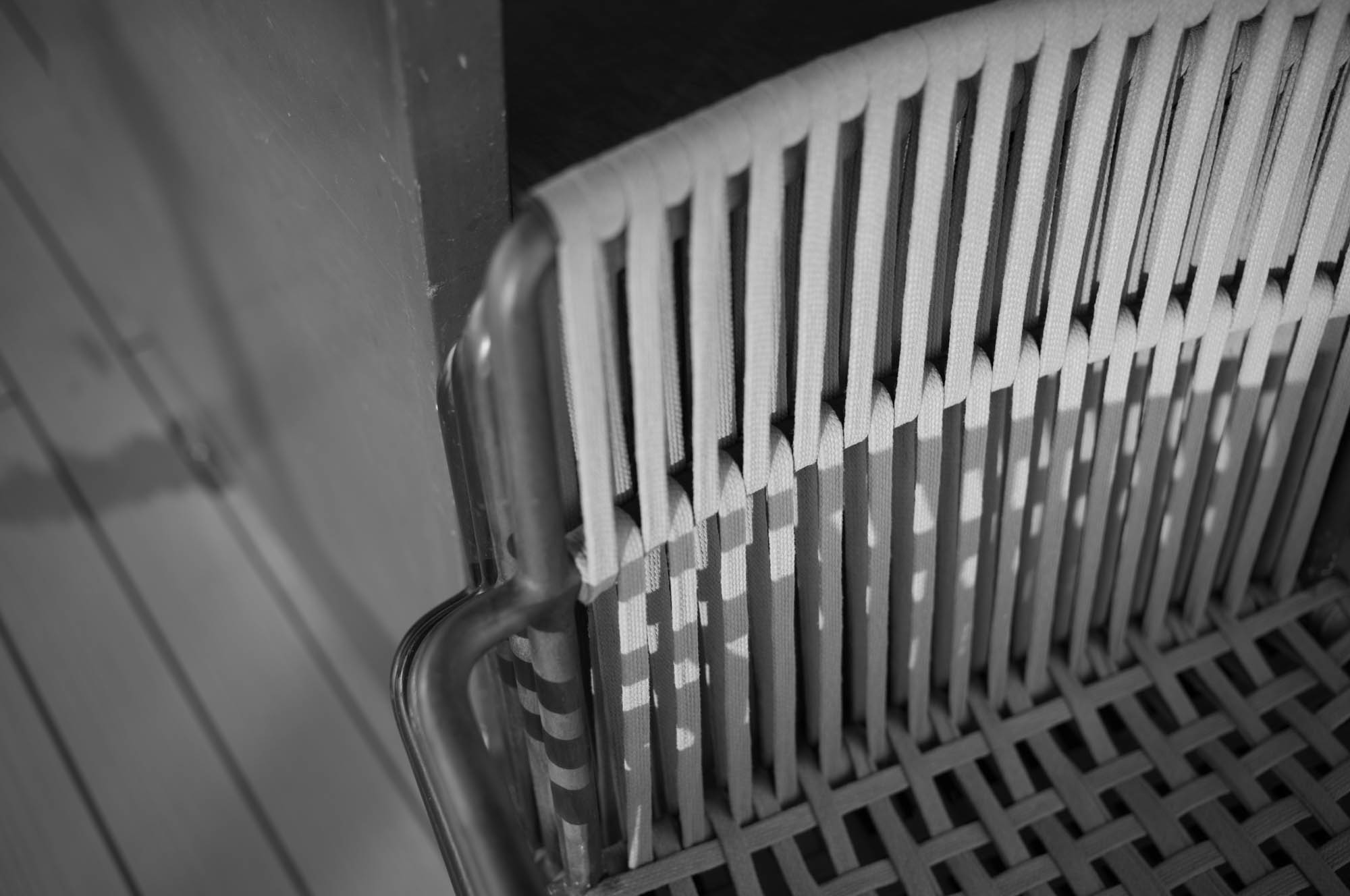 Black and white woven chair detail with shadows, showcasing intricate pattern and texture design.