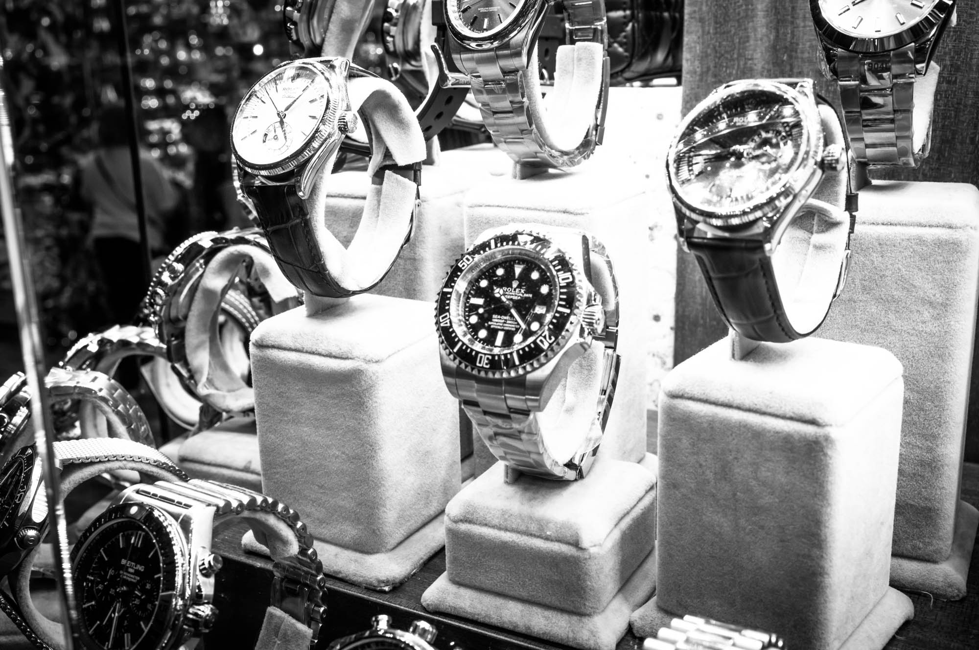 Luxury watches displayed on velvet stands in a store showcase, showcasing elegant timepieces.
