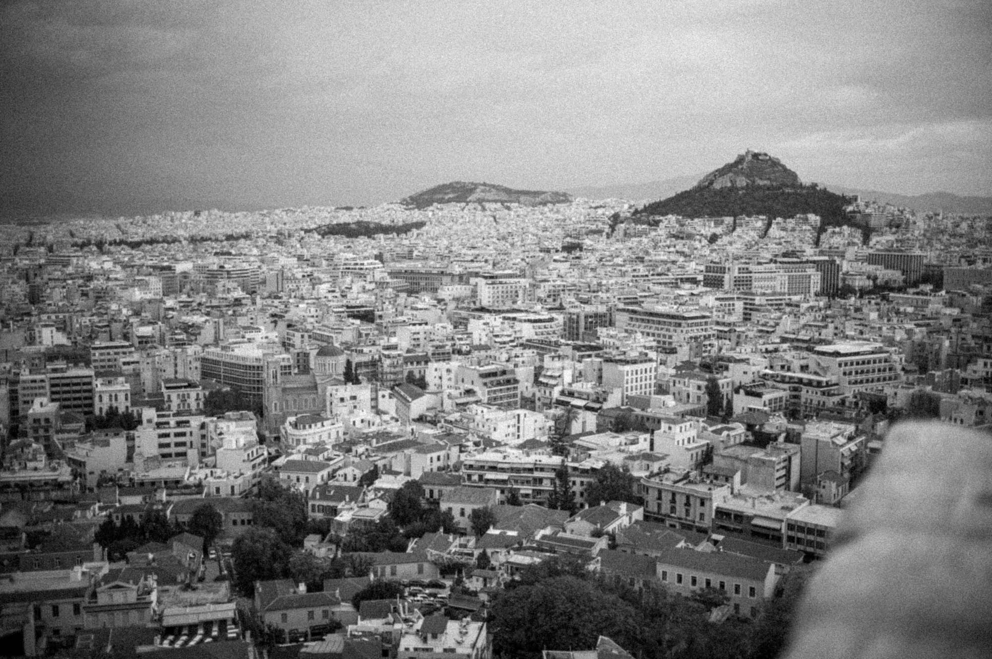 Black and white aerial view of Athens, Greece with Mount Lycabettus in the distance.