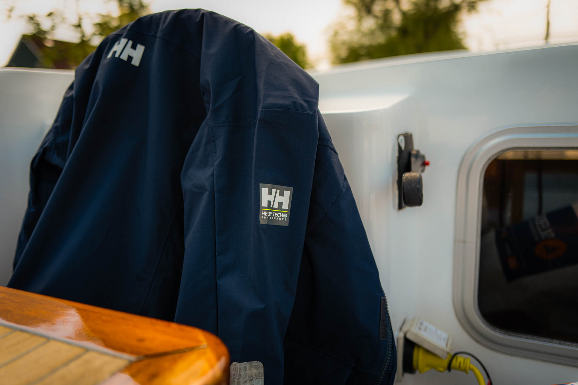 Navy jacket with logo hanging inside a boat near a window, emphasizing outdoor adventure and durability.