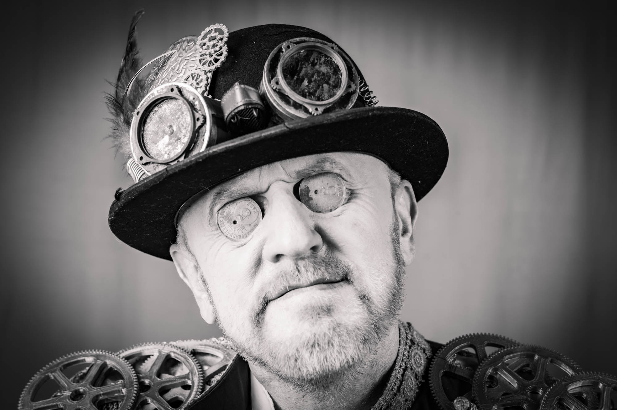 Steampunk enthusiast with goggles and gears, showcasing unique style and creativity. Black and white portrait.
