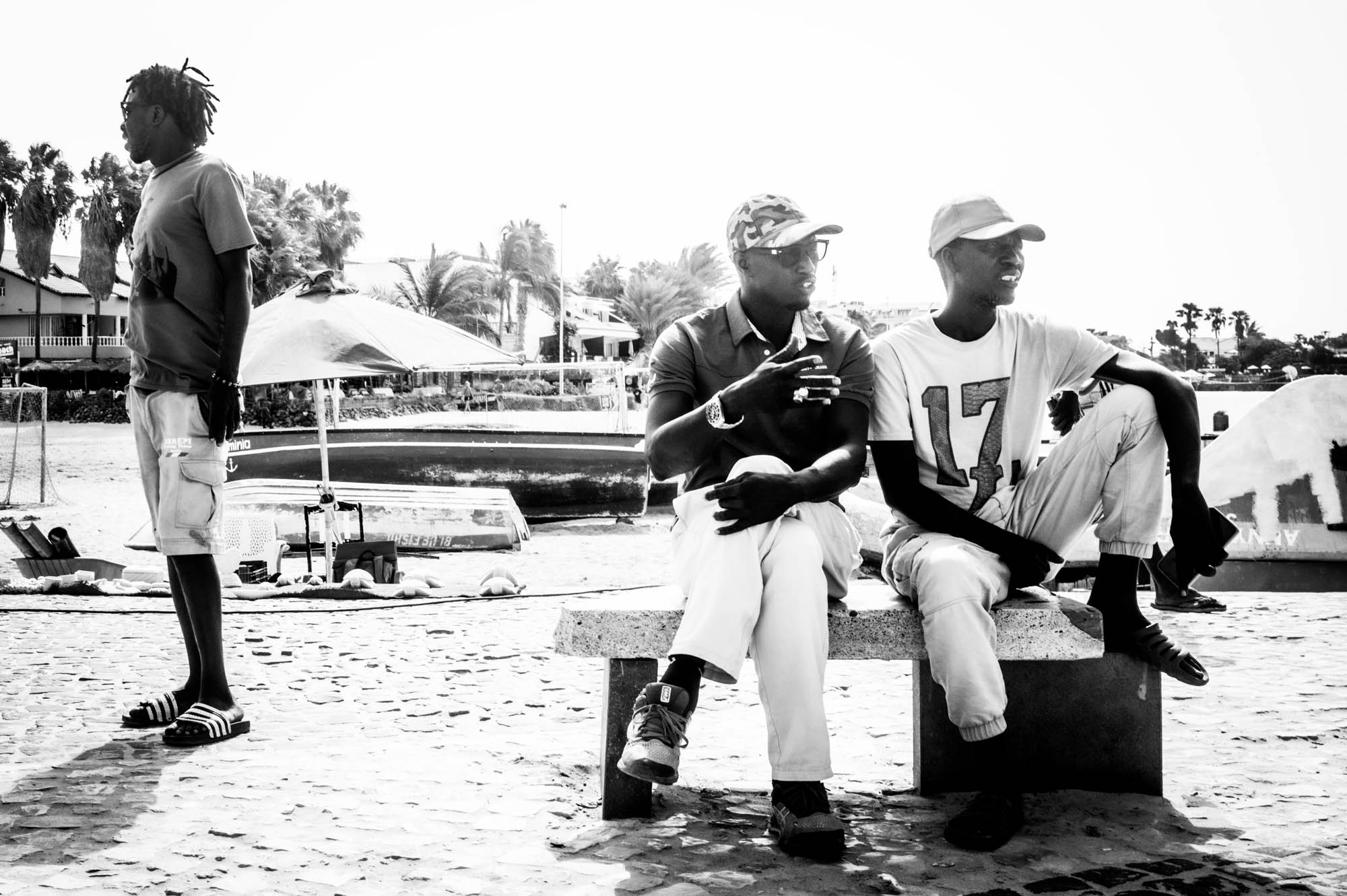 Men talking and relaxing on a sunny day by the beach, black and white photo.