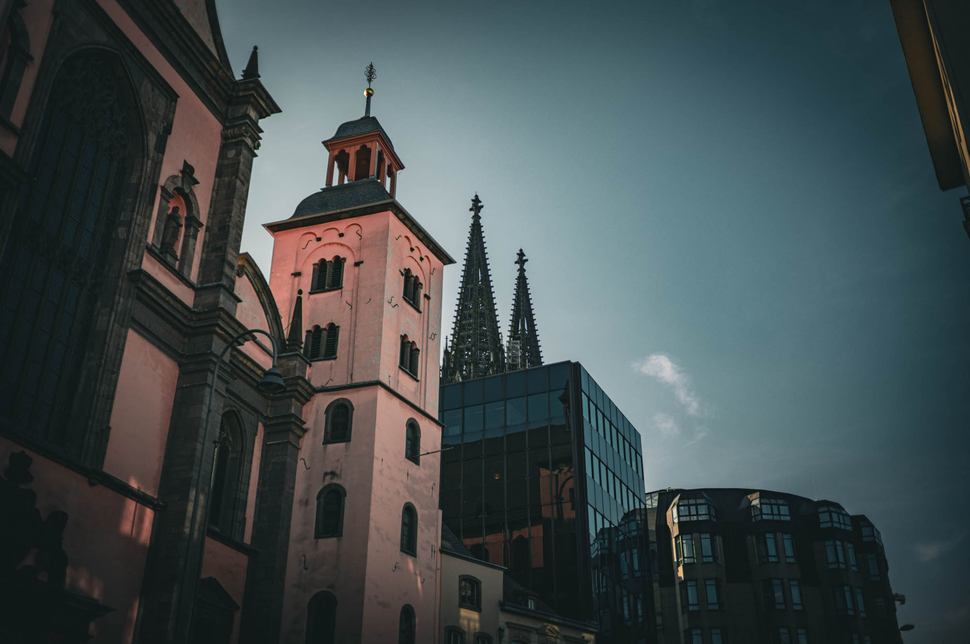 Historical and modern architecture contrast in a sunset cityscape with gothic and contemporary buildings.