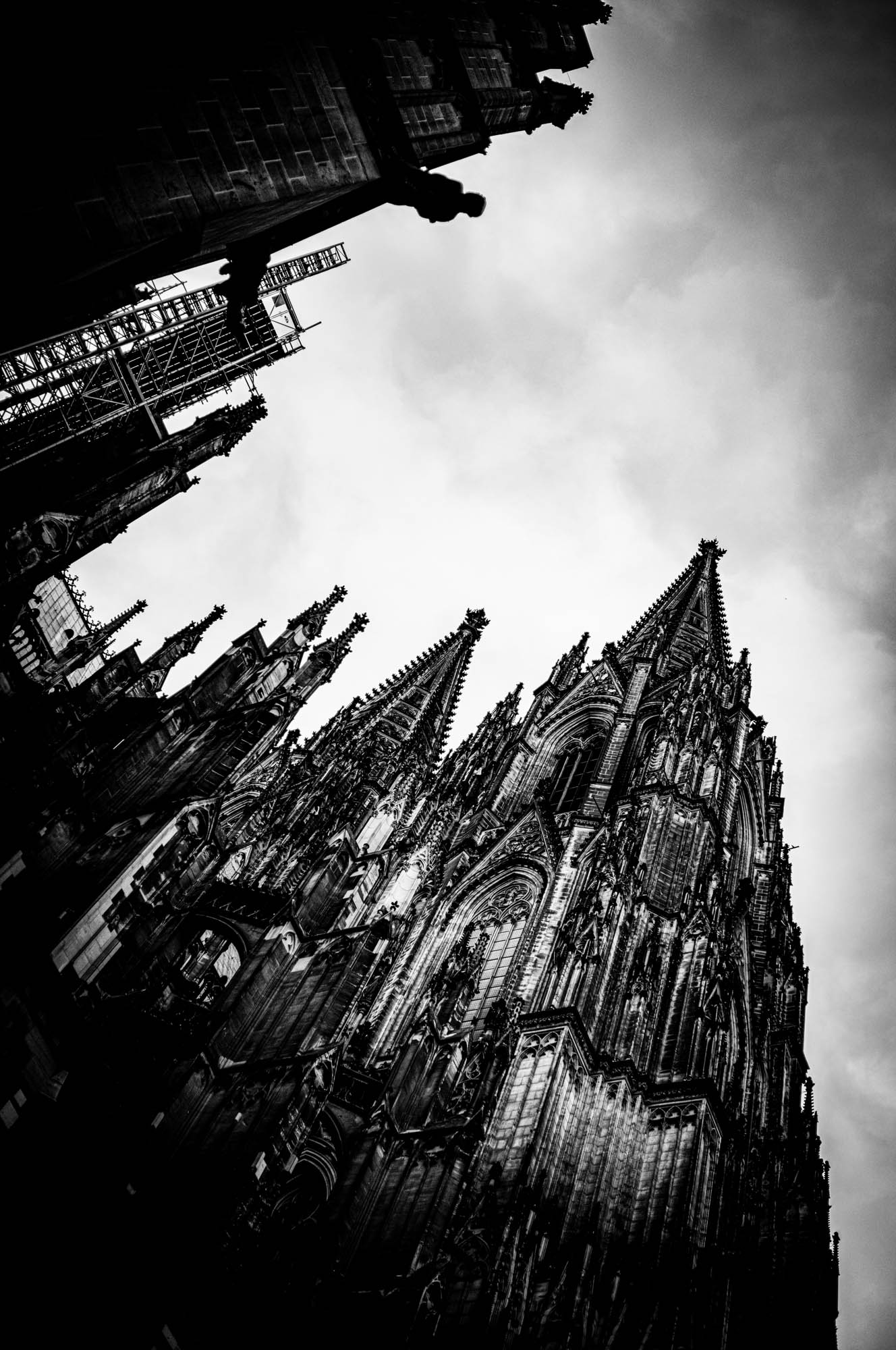 Dramatic black and white photo of a gothic cathedral with towering spires against a cloudy sky.