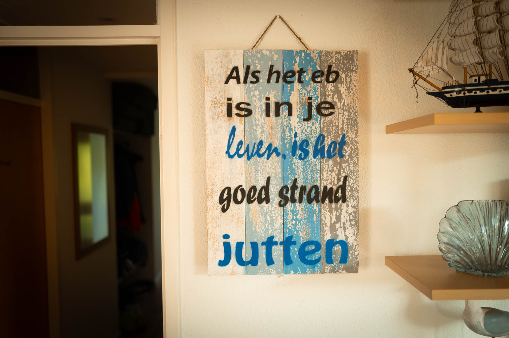 Decorative sign on wall with Dutch quote, surrounded by nautical decor.