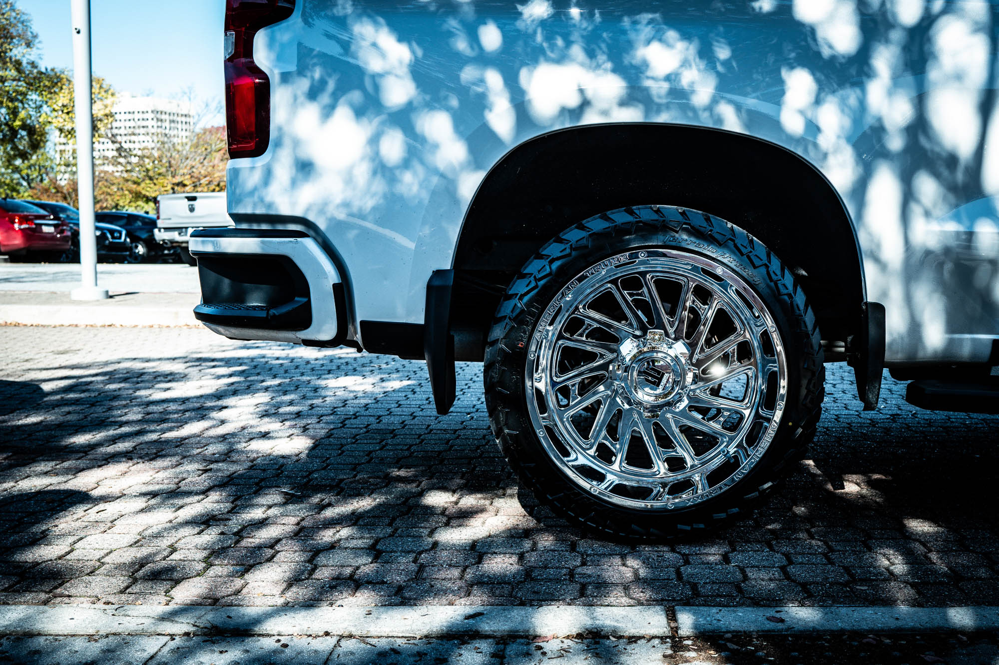 Close-up of a shiny chrome wheel on a parked truck, highlighting intricate design in daylight.