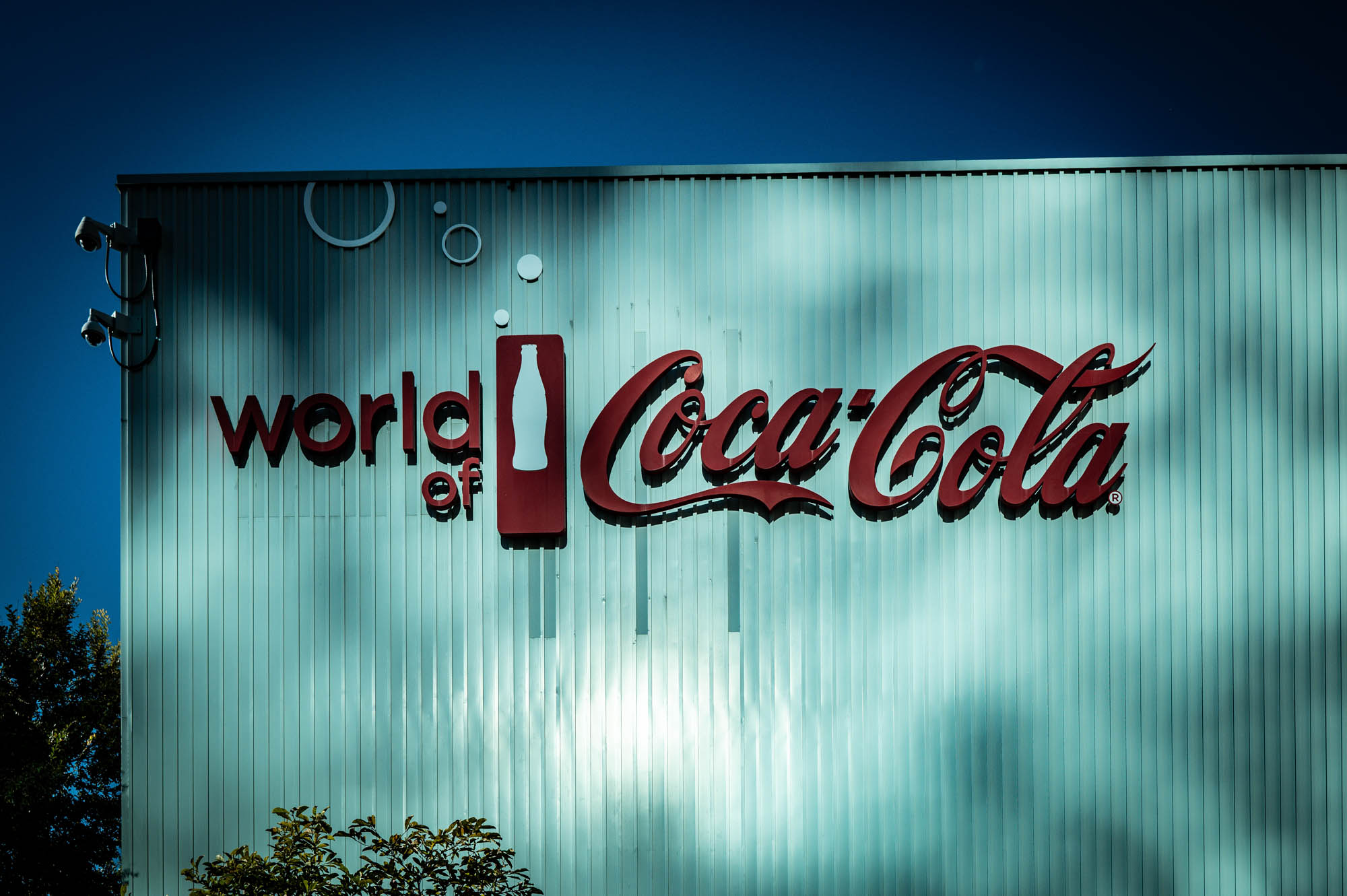 World of Coca-Cola sign on building, showcasing iconic red logo and bottle silhouette.
