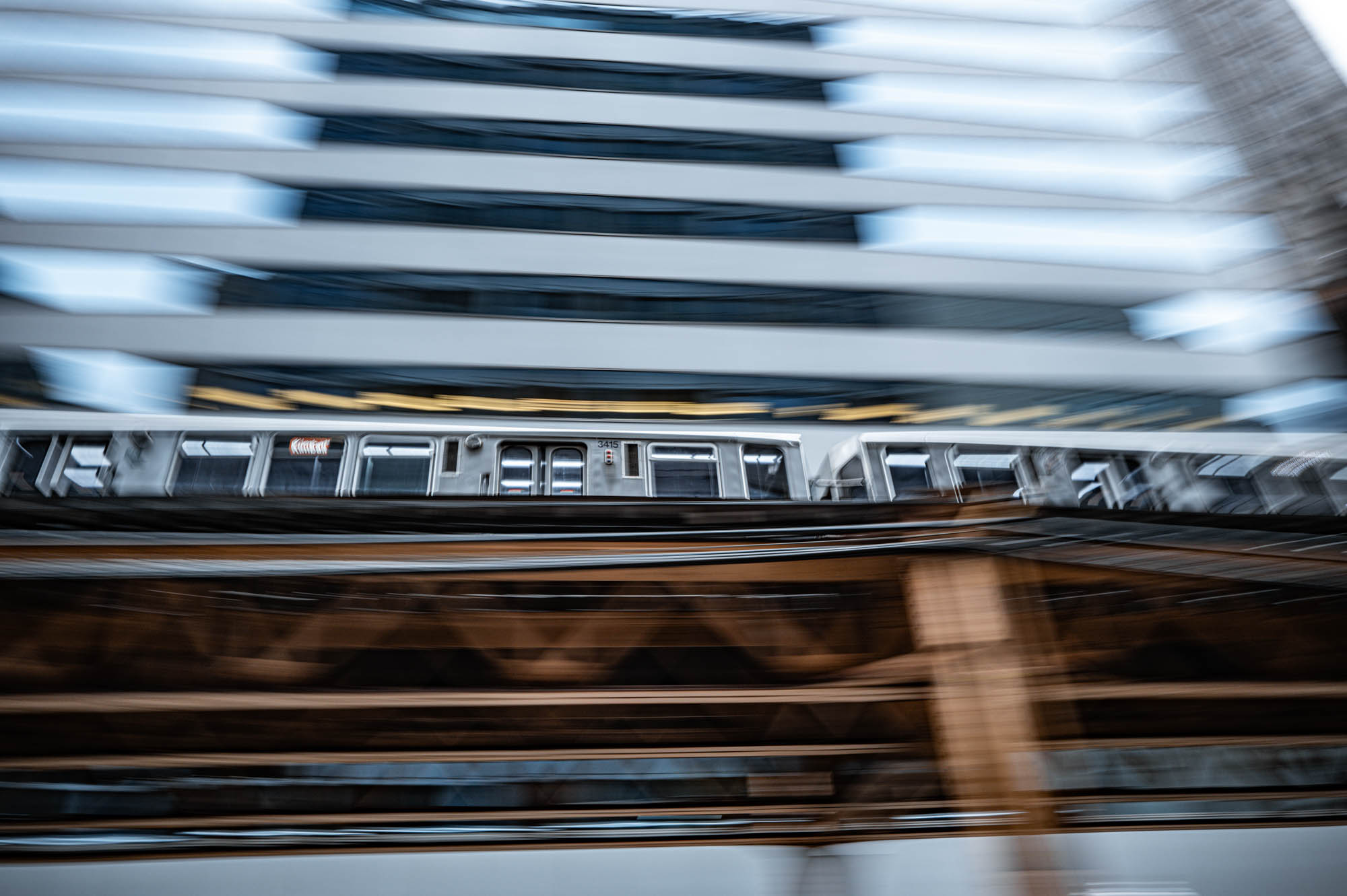 Blurred motion of a train speeding past a modern building, creating a dynamic urban scene.