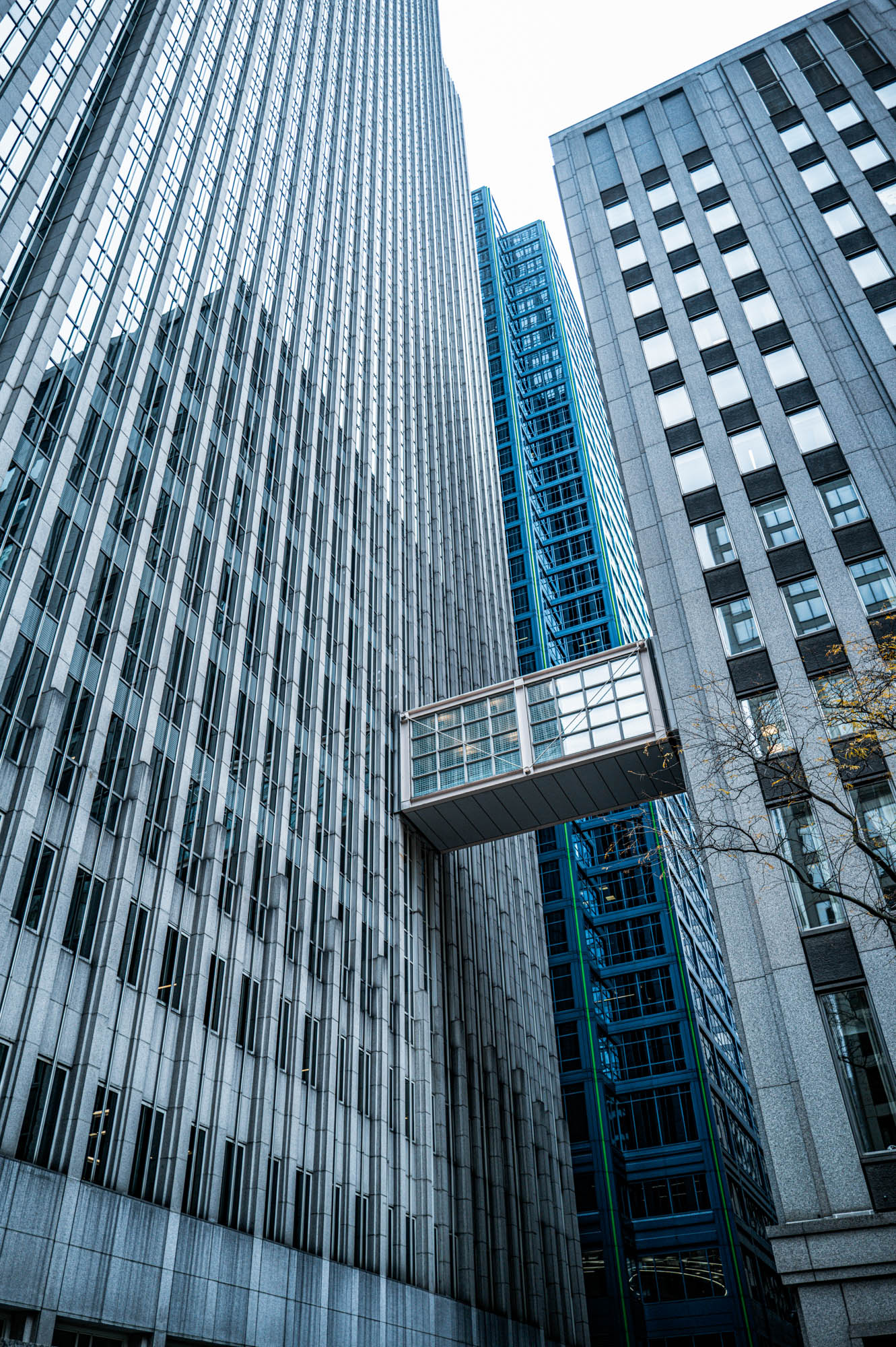 Modern skyscrapers with connecting skybridge, showcasing urban architecture under a cloudy sky.