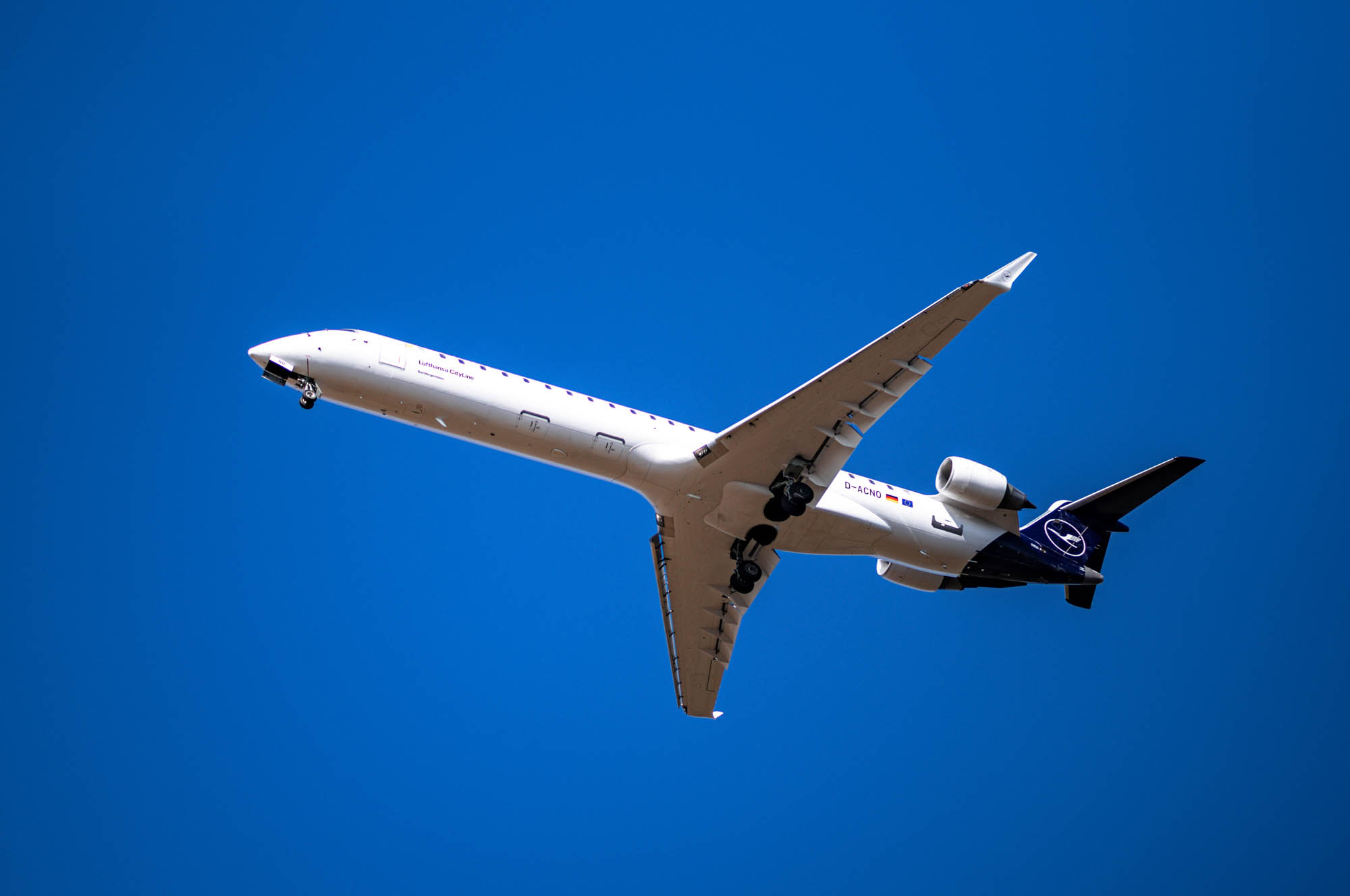 Passenger airplane flying against a clear blue sky, captured from below.