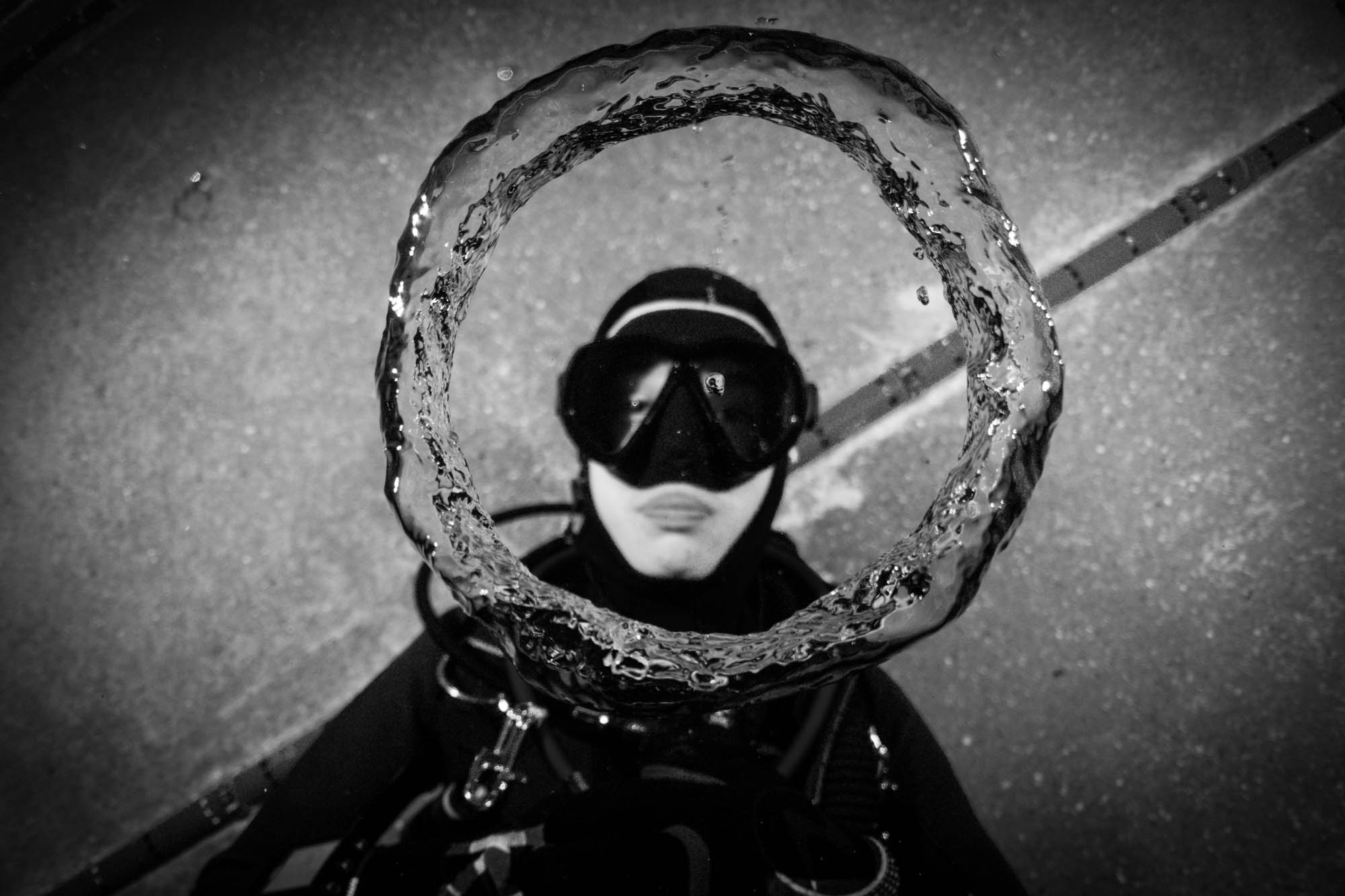 Diver underwater blowing perfect bubble ring, black and white photography.
