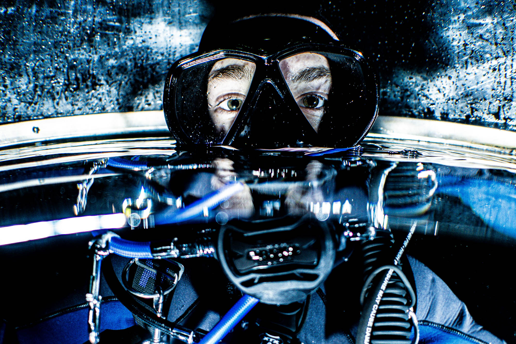Diver in scuba gear with mask above waterline, ready for underwater exploration.