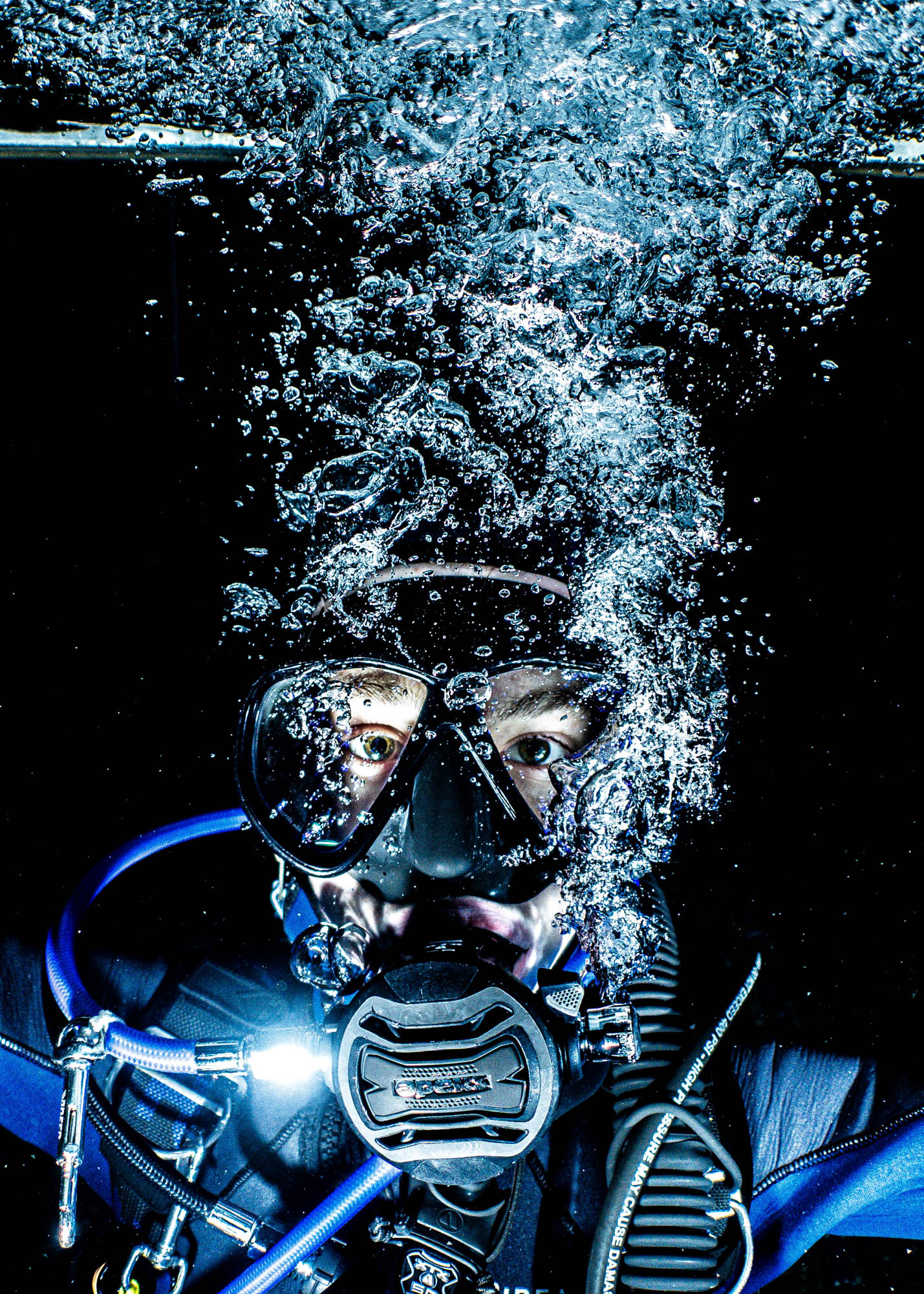 Diver underwater with bubbles, wearing scuba gear and mask in deep sea exploration.