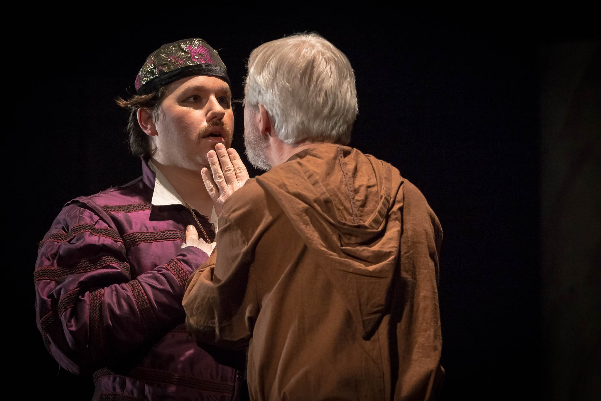 Two actors in a dramatic scene; one in a purple costume, the other in brown, intensely engaged on stage.