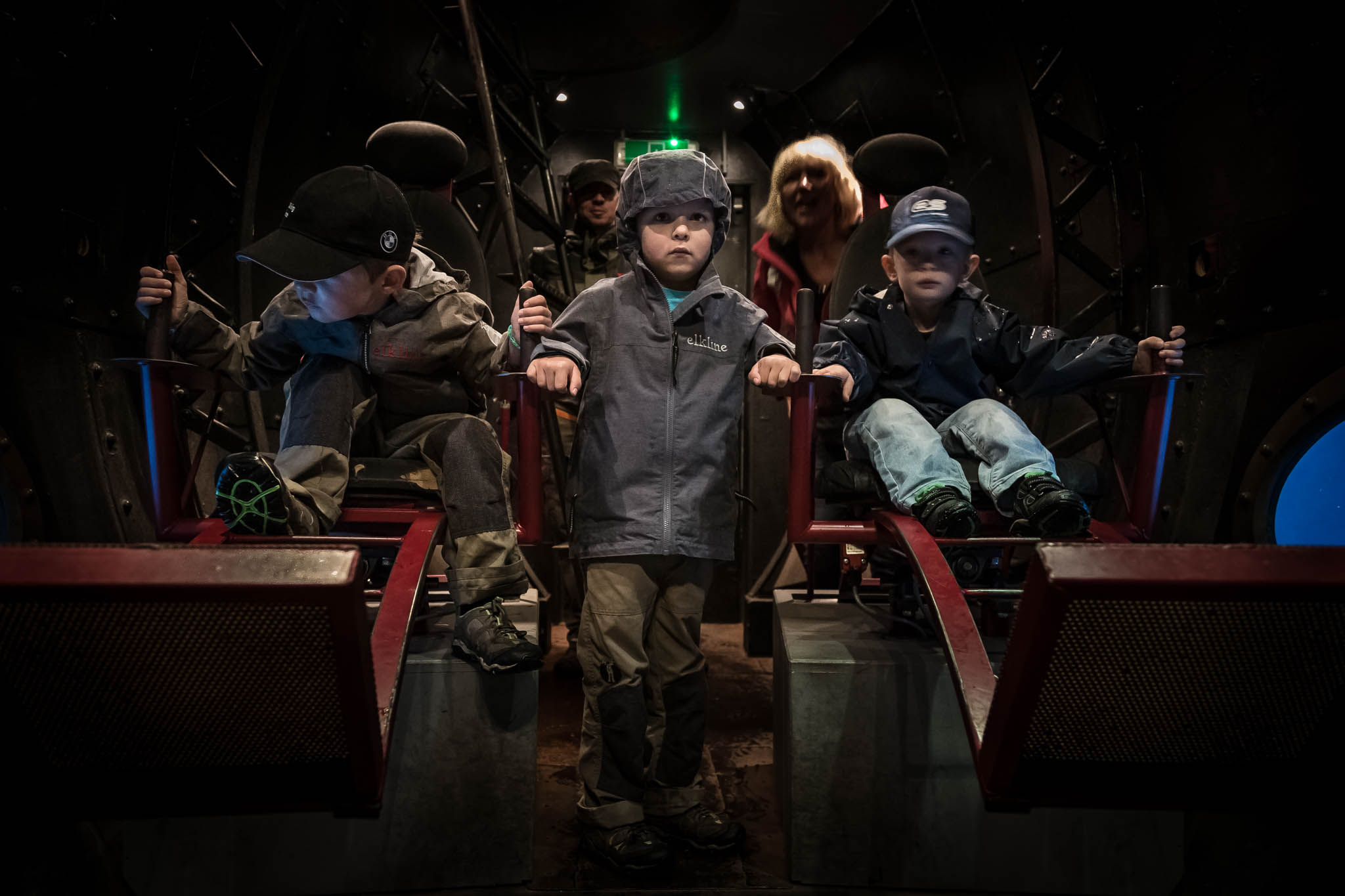 Children in a dark room operating levers, engaged in an interactive exhibit or ride experience.