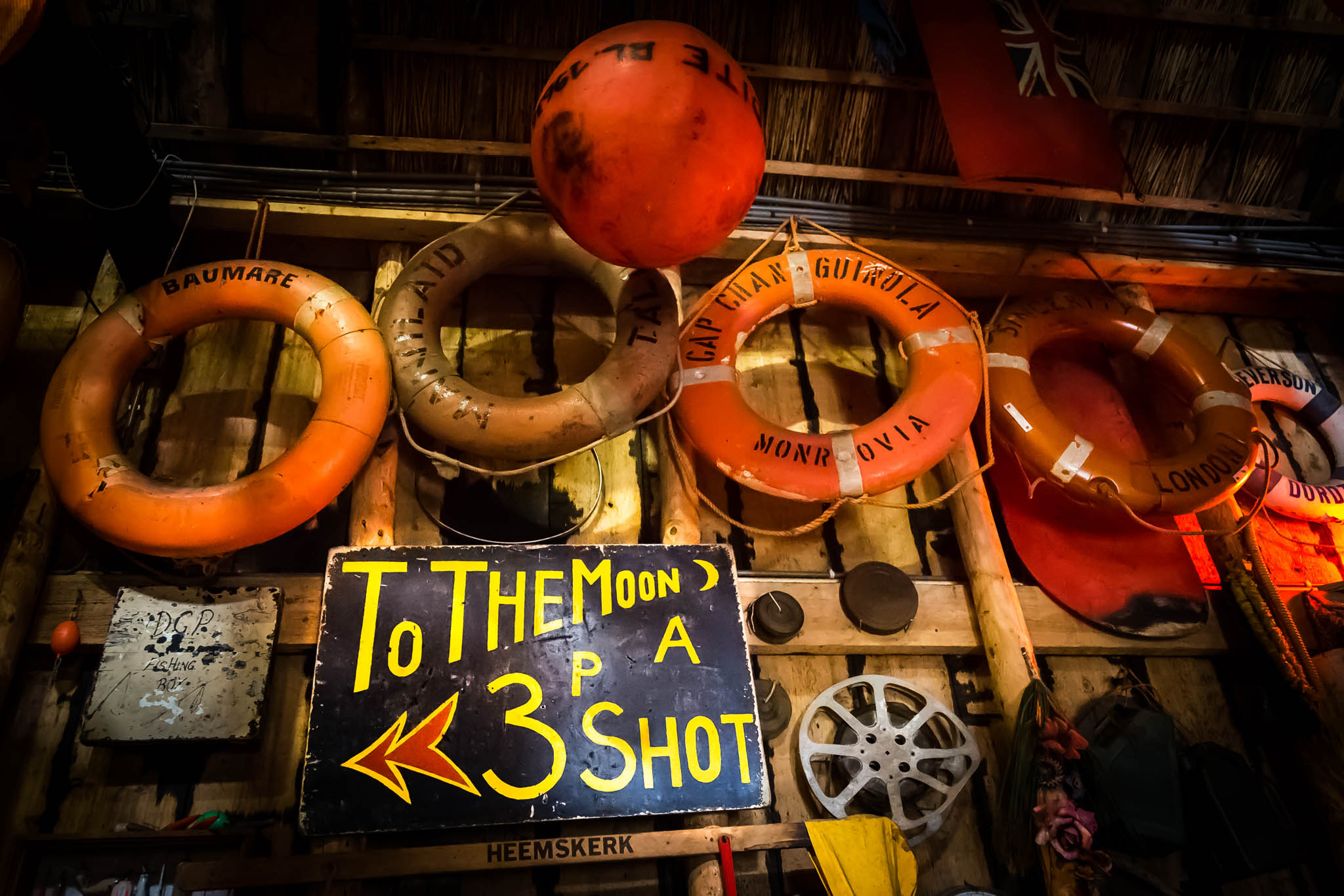 Vintage lifebuoys and a colorful To The Moon sign in a rustic setting, creating a nautical-themed decor.