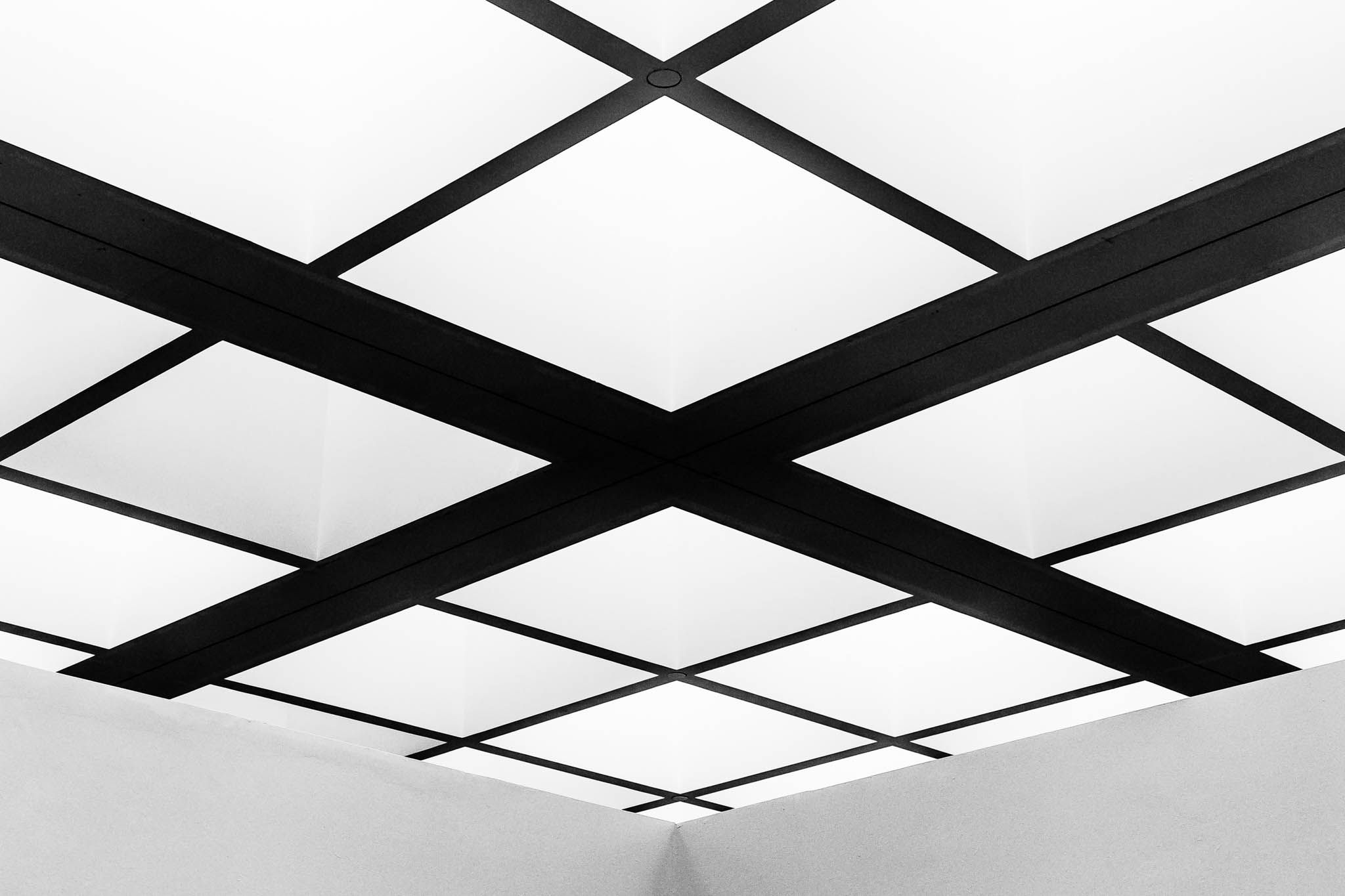 Geometric black and white ceiling with crisscross design and grid pattern.