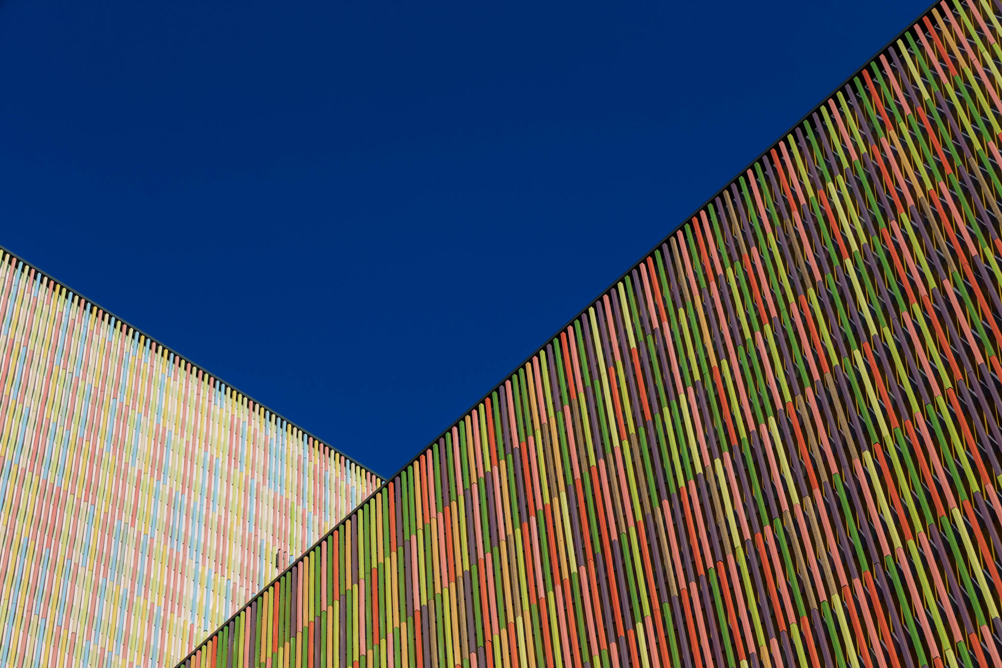 Colorful geometric building facades with vertical stripes under a clear blue sky.