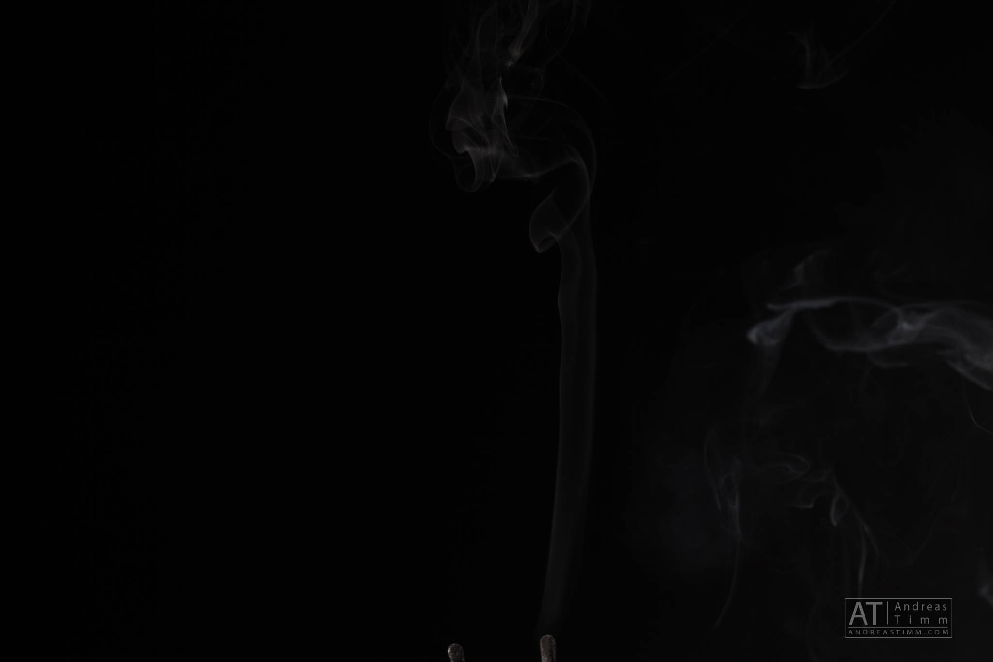 Delicate wisps of smoke rising against a black background, creating an ethereal and mysterious ambiance.