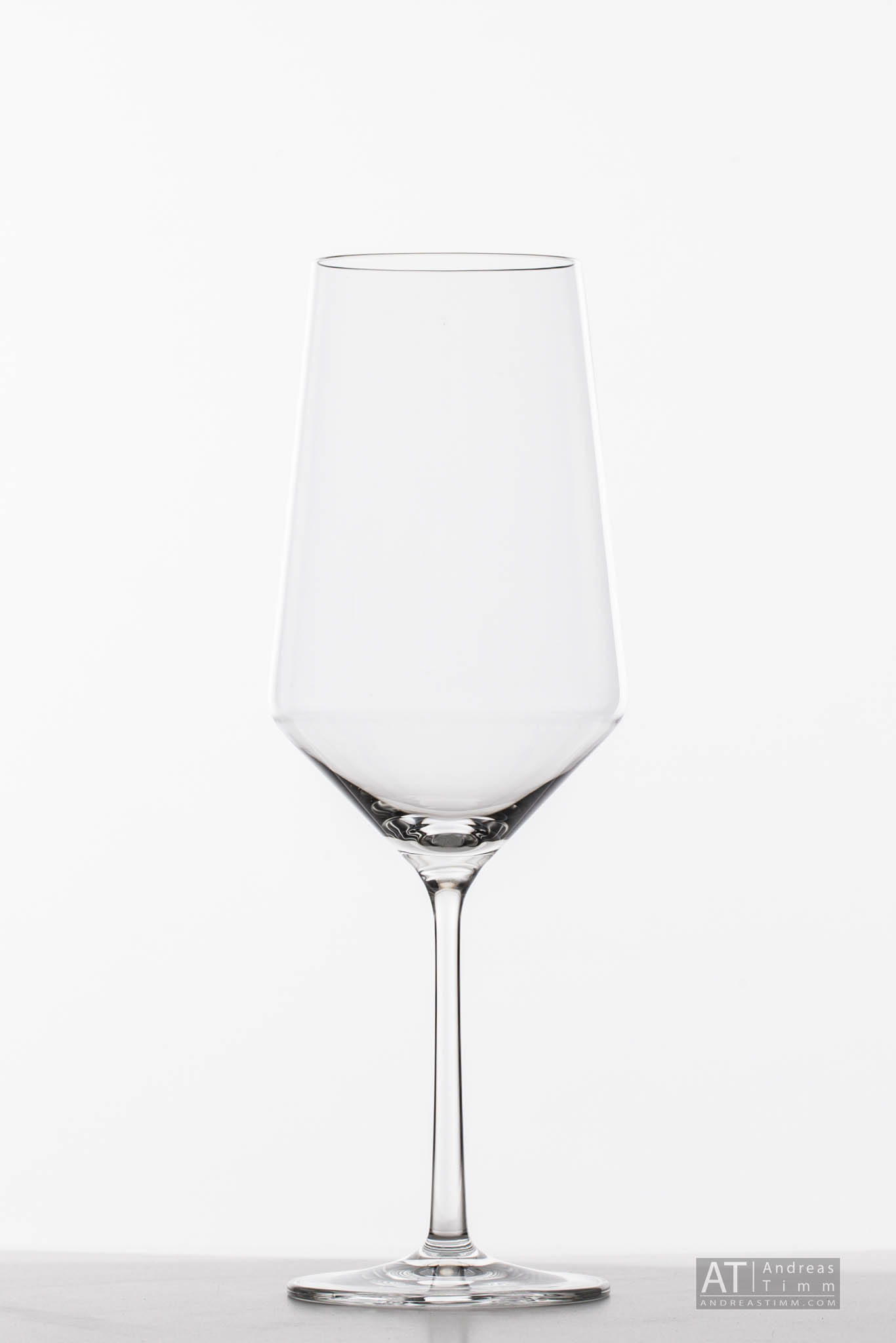 Tall, empty wine glass on a white background with a sleek design, ideal for elegant dining settings.