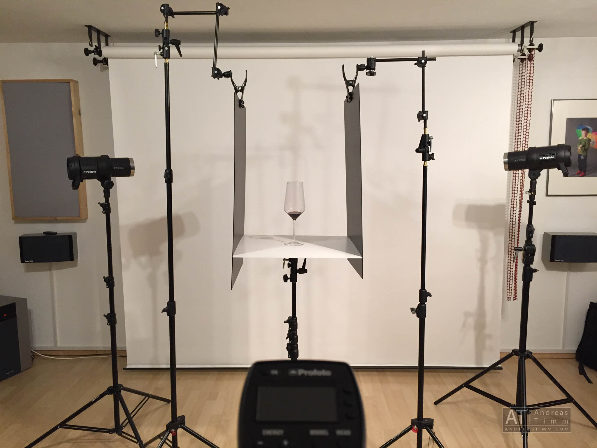 Studio photography setup with a wine glass on a table, surrounded by professional lighting equipment.
