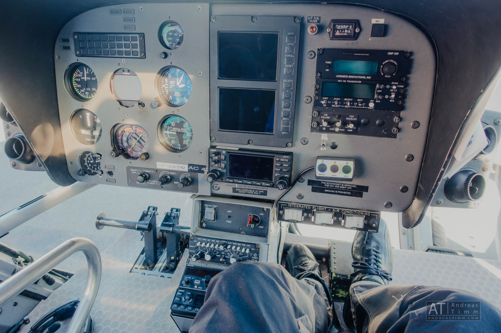 Helicopter cockpit with detailed control panel and gauges, pilot's legs visible, showcasing aviation equipment.
