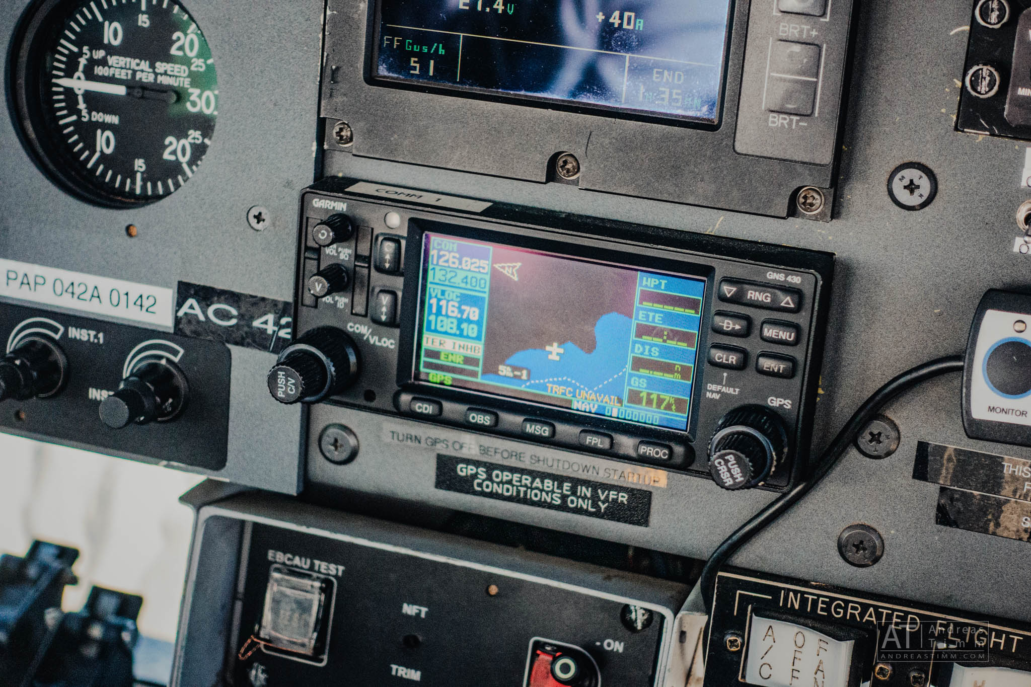 Close-up of airplane cockpit instruments, including Garmin GPS display and speed gauge, showing navigation data.