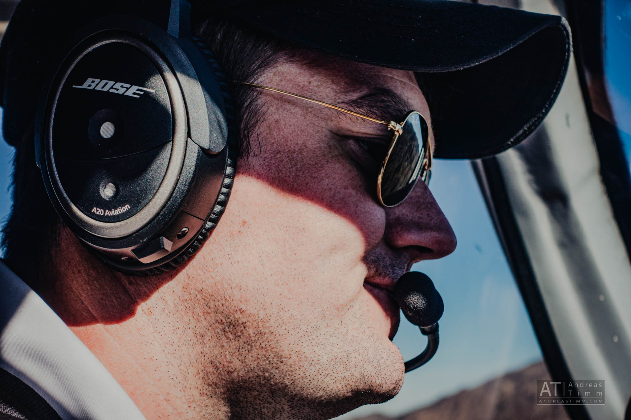 Pilot wearing Bose A20 aviation headset and sunglasses inside an aircraft cockpit.