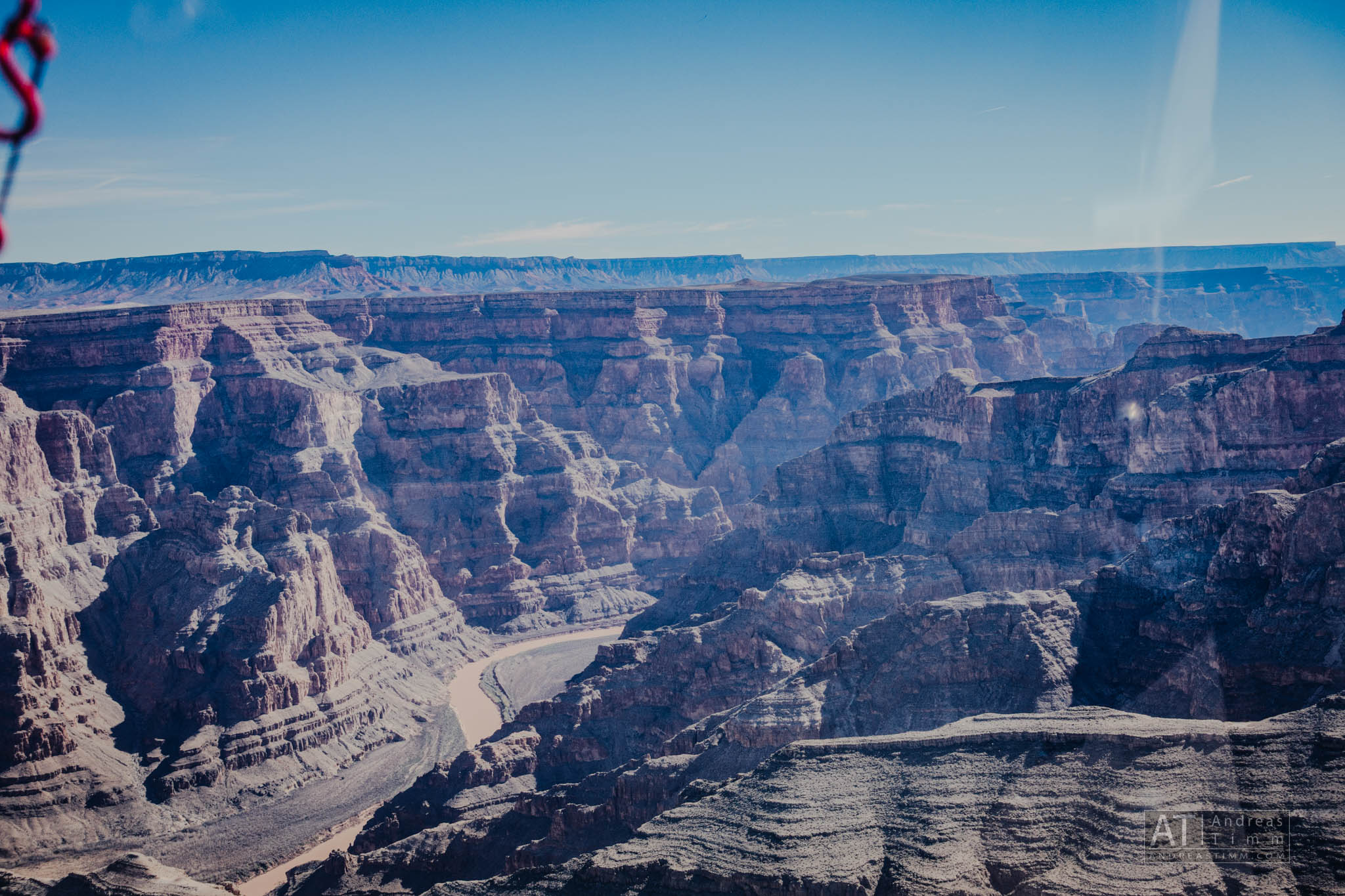 View of the Grand Canyon's rugged landscape with a winding river under a clear blue sky.